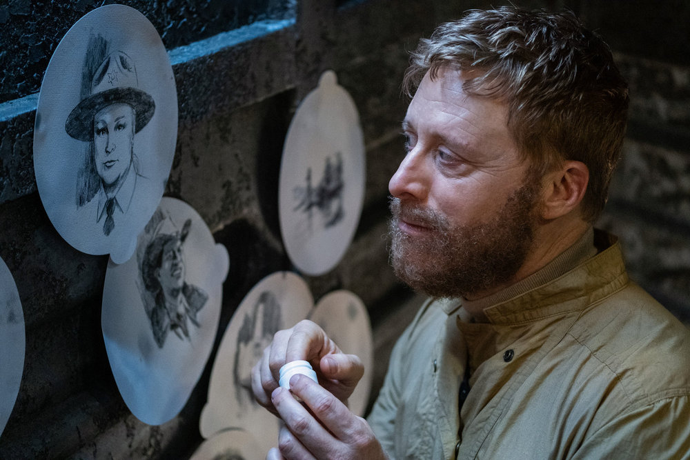 Harry (Alan Tudyk) looks sadly at sketches of Elizabeth Bowen’s Deputy Liv Baker and Corey Reynolds’ Sheriff Mike Thompson in season 4 of Resident Alien Harry (Alan Tudyk) looks sadly at sketches of Elizabeth Bowen’s Deputy Liv Baker and Corey Reynolds’ Sheriff Mike Thompson in season 4 of Resident Alien