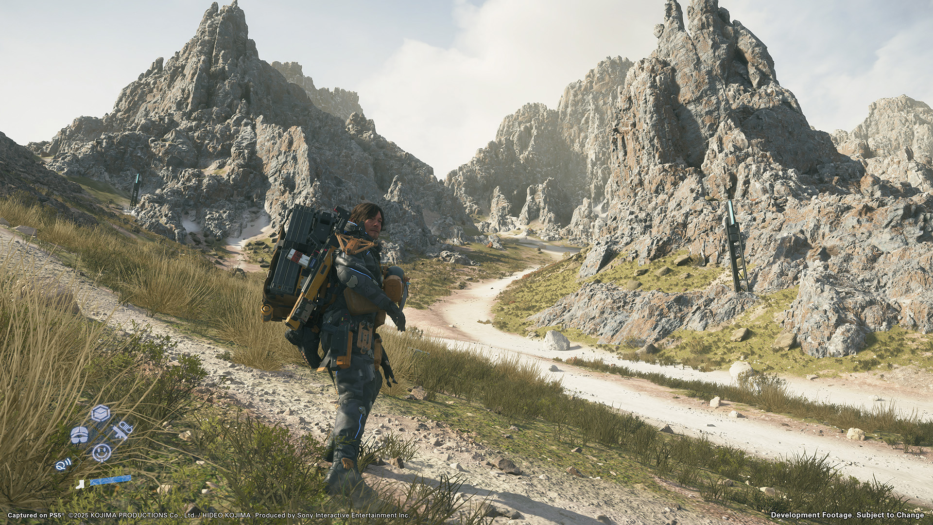 Sam Bridges stands before a rugged mountain landscape in Death Stranding 2 Sam Bridges stands before a rugged mountain landscape in Death Stranding 2