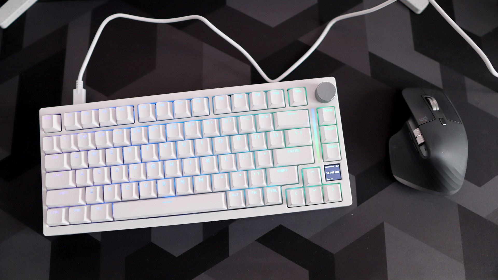 A Gamakay TK75HE gaming keyboard in white on a black and grey mouse pad with RGB lighting enabled.