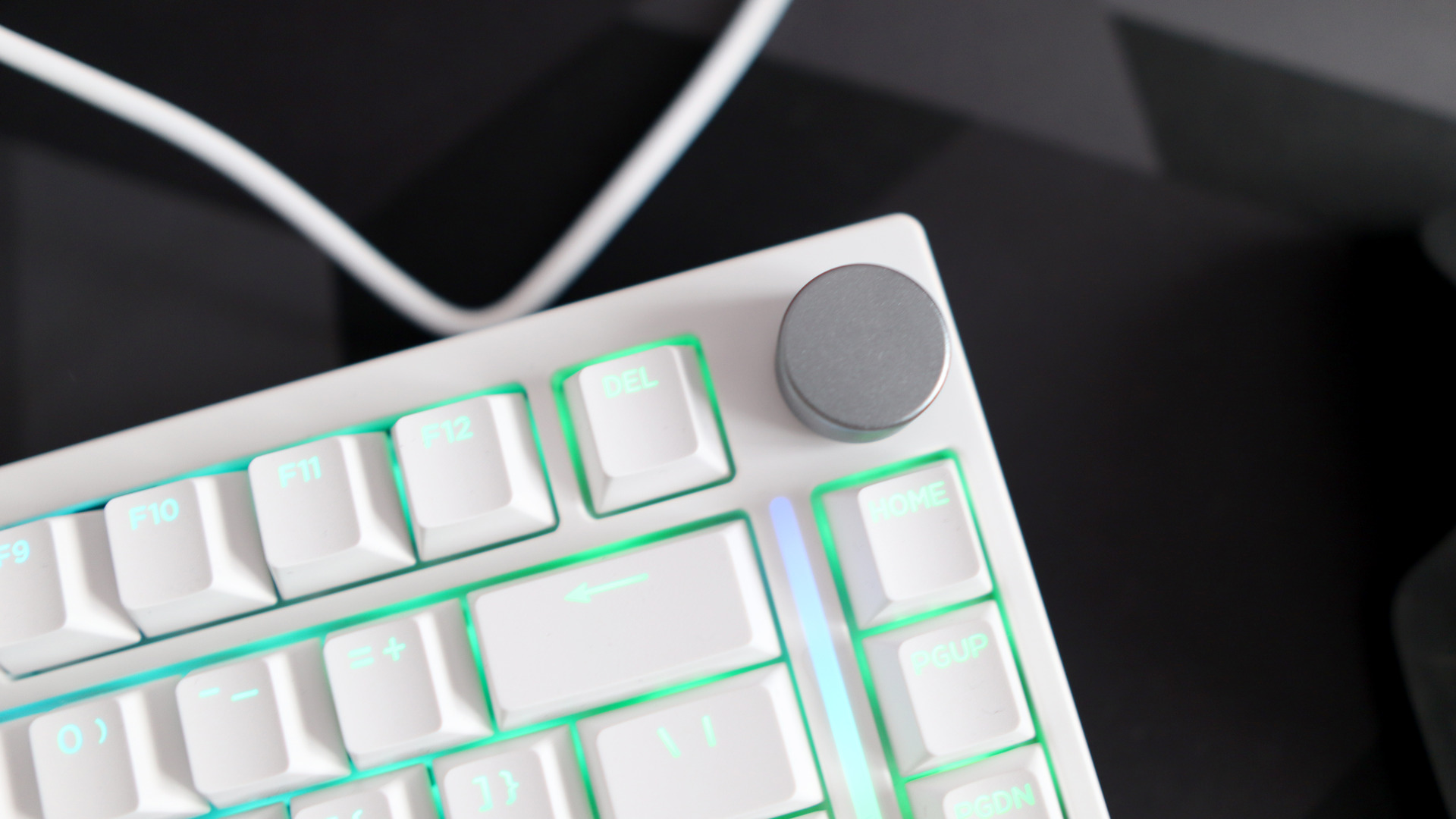 A Gamakay TK75HE gaming keyboard in white on a black and grey mouse pad with RGB lighting enabled.
