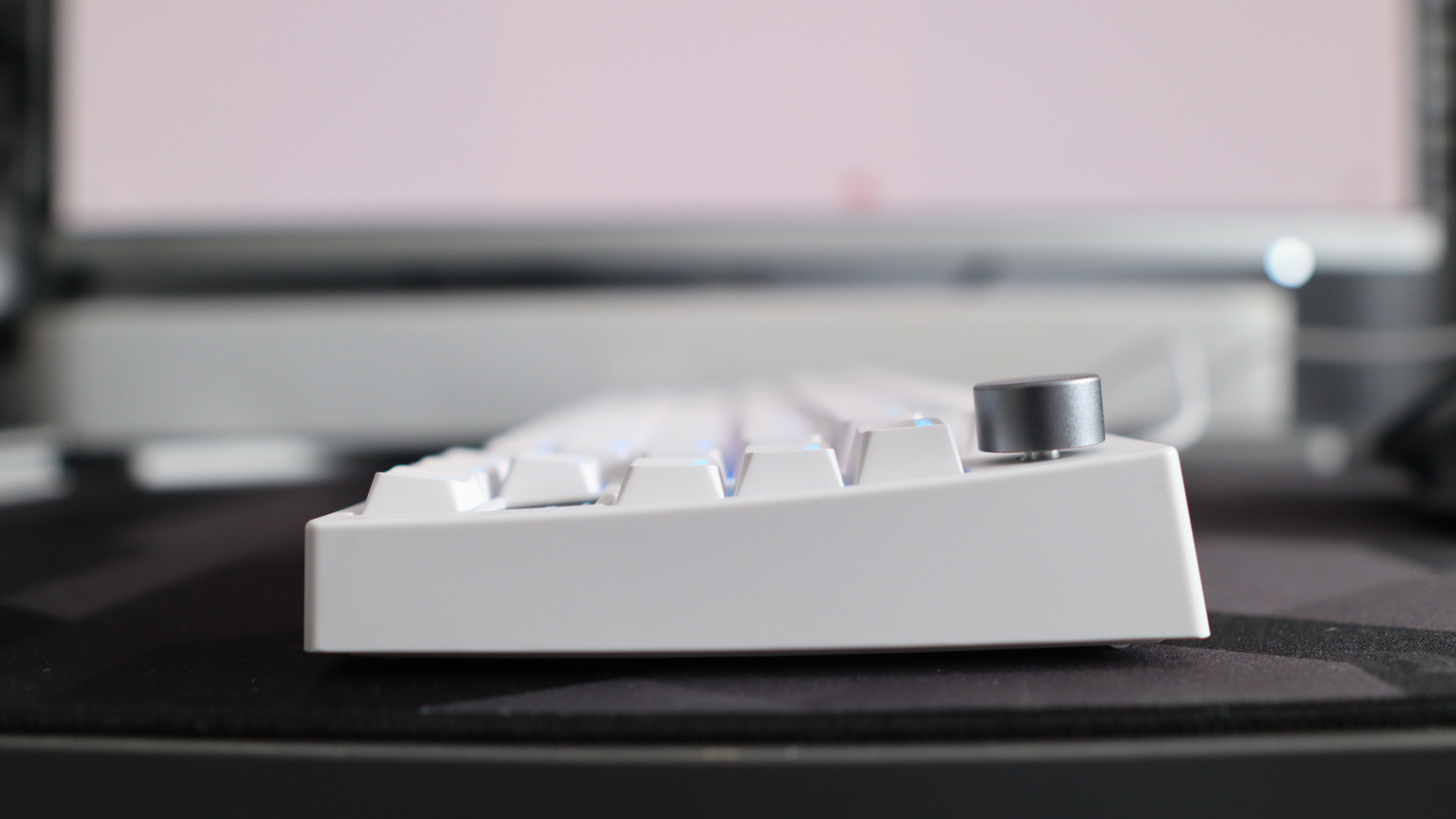 A Gamakay TK75HE gaming keyboard in white on a black and grey mouse pad with RGB lighting enabled.