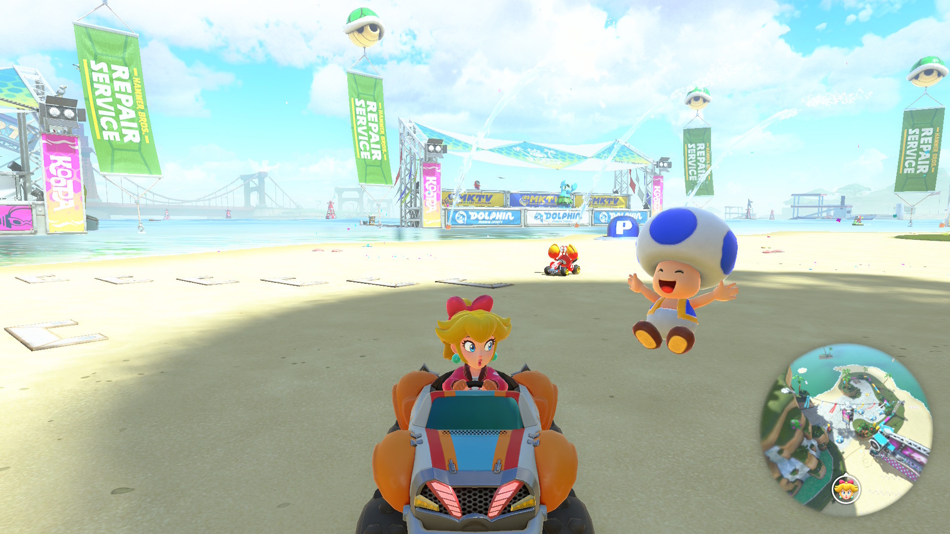 Peach looking surprised as a Toad waves at her on the Koopa Beach course in Mario Kart World Peach looking surprised as a Toad waves at her on the Koopa Beach course in Mario Kart World