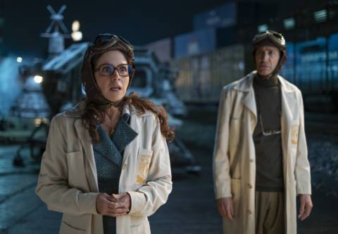 Lucero as Nora and Benny Ibarra as Héctor wear lab coats and aviator hats and goggles as they stand in front of a time machine in 2025 Mexico in Our Times.