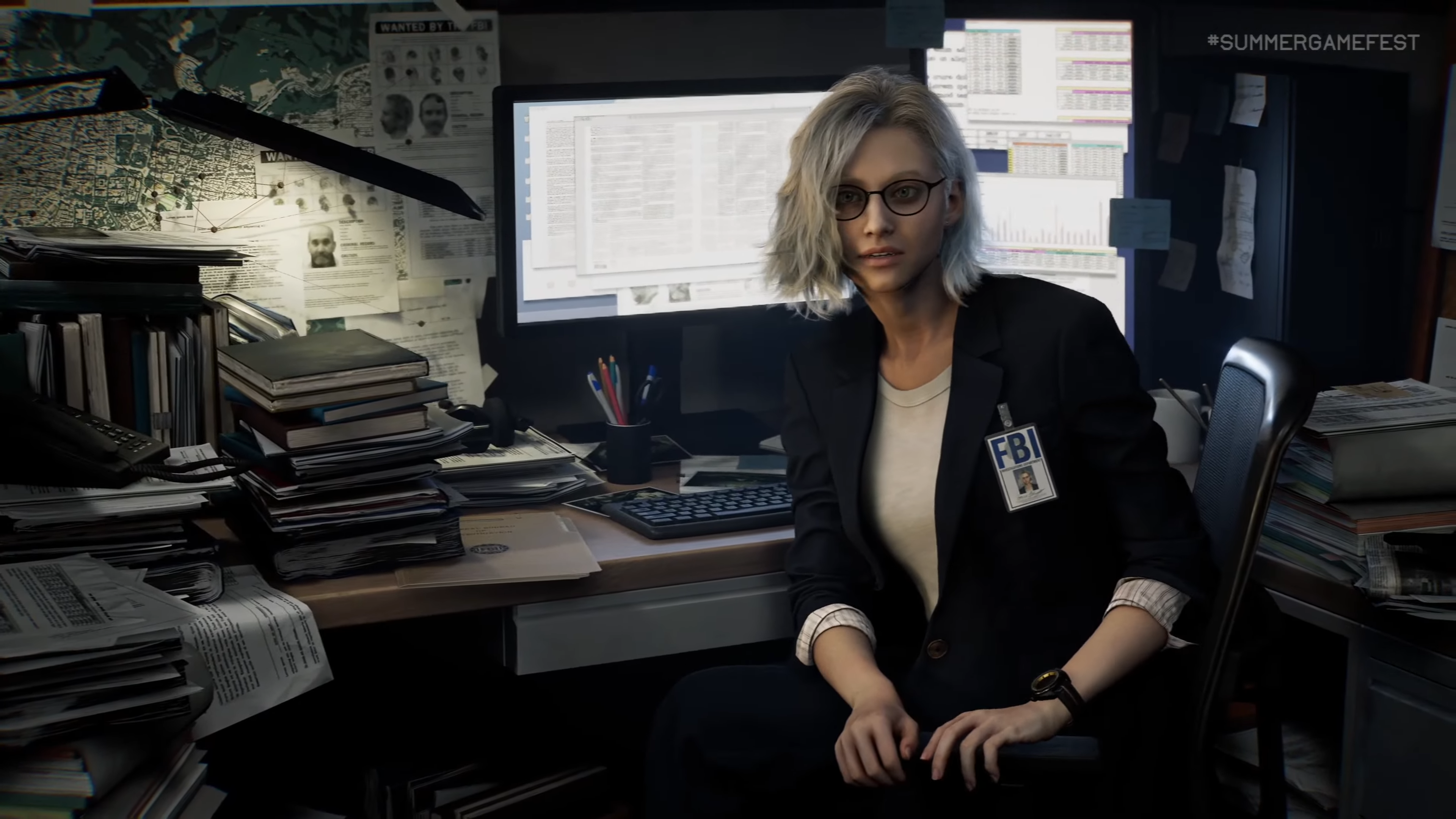 A screenshot of Grace, a blond woman with glasses, sitting in front of a messy office cubicle A screenshot of Grace, a blond woman with glasses, sitting in front of a messy office cubicle