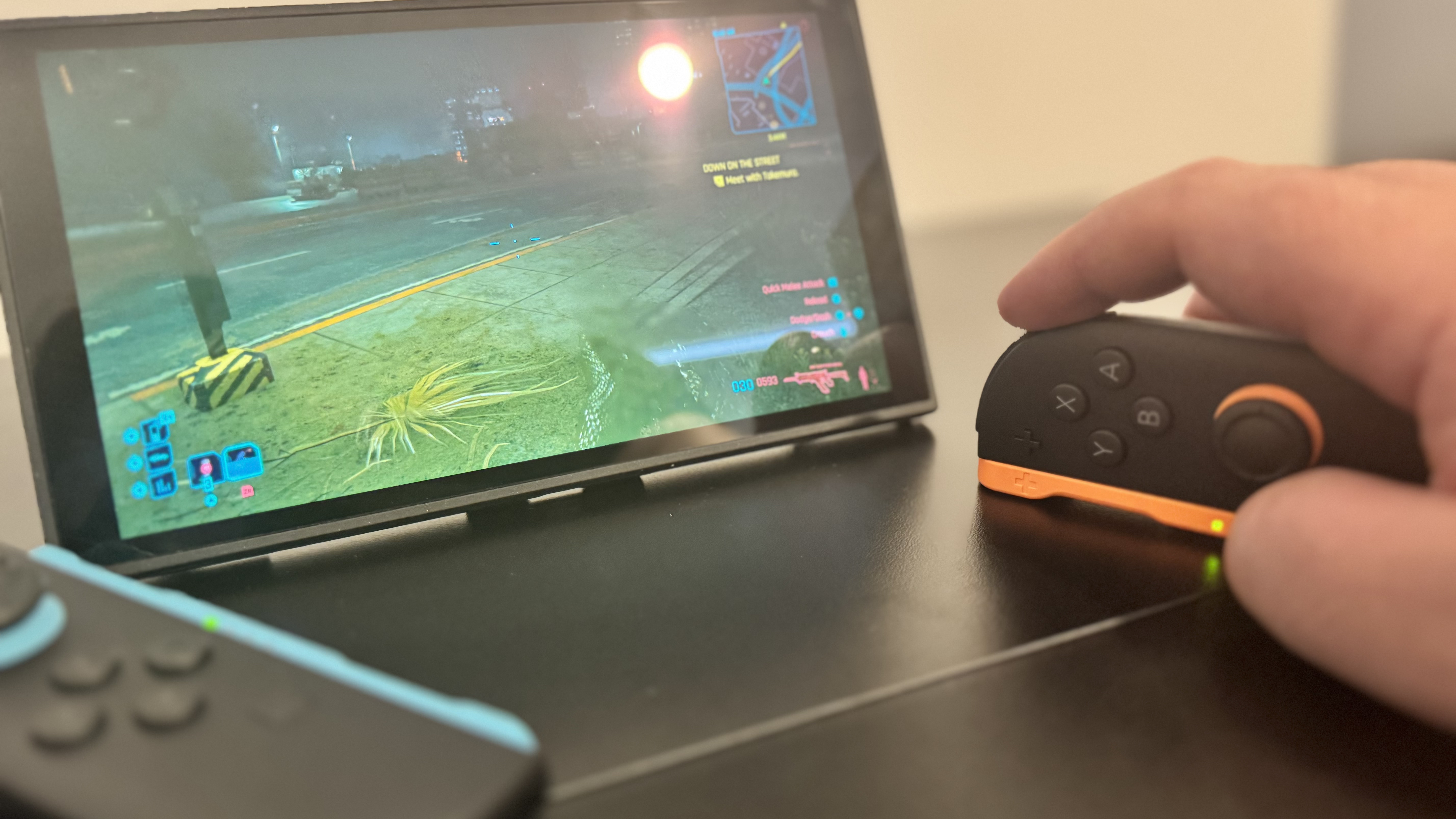 A picture of a Nintendo Switch 2, in mouse mode, with Cyberpunk 2077 in the background