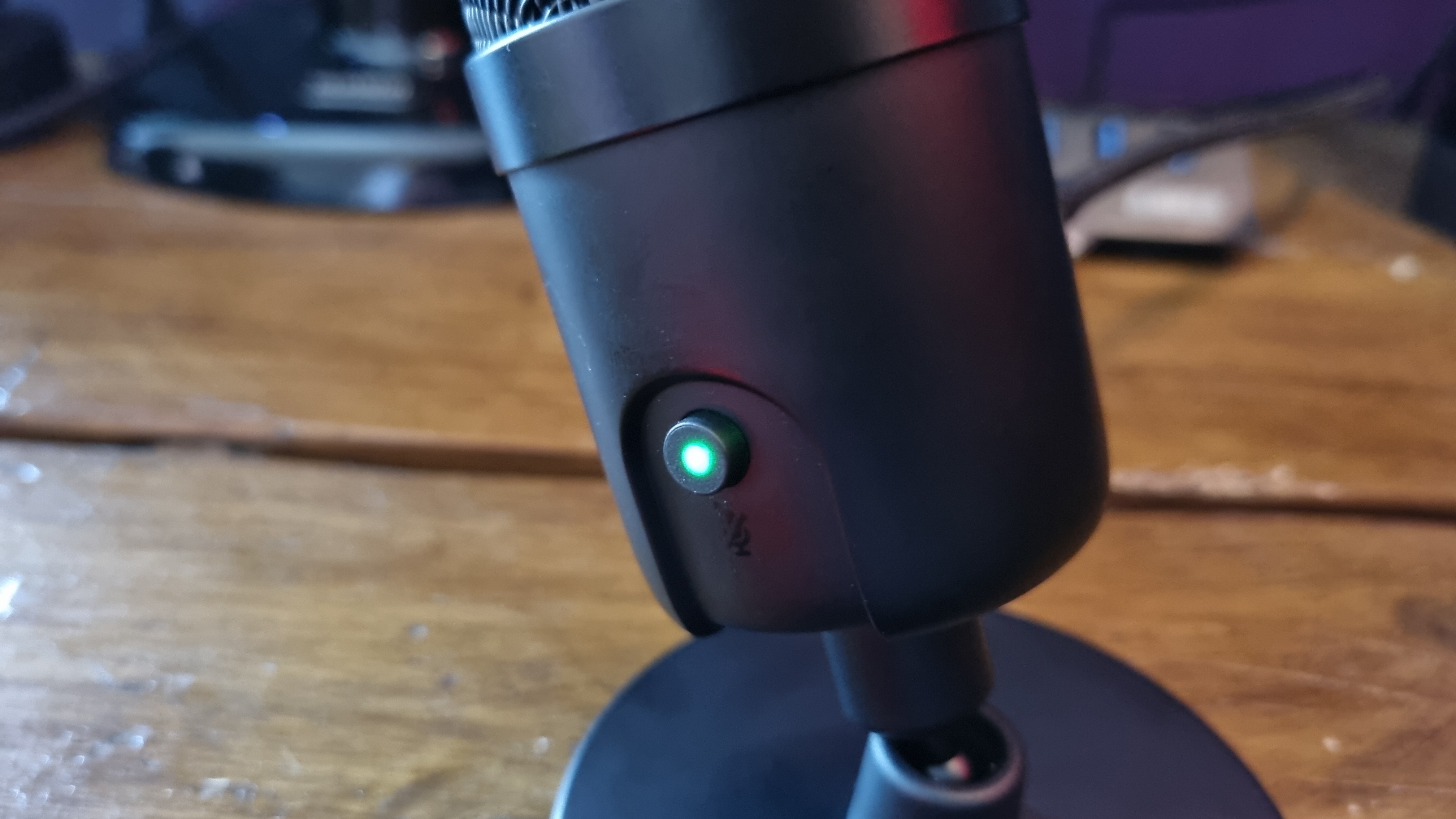 The Amazon Basics USB condenser microphone with its mute button off, showing a green LED