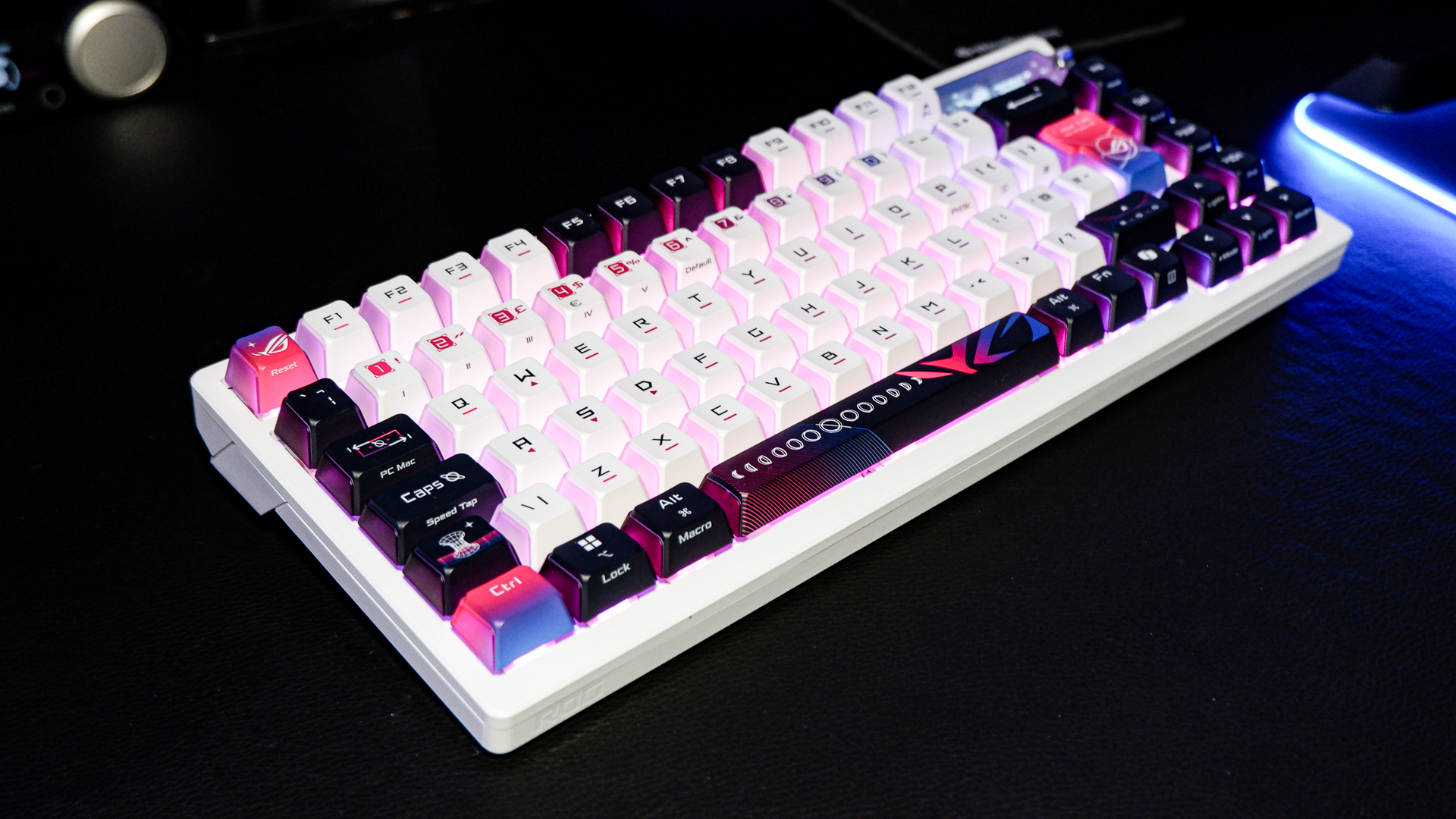 An Asus ROG Azoth X gaming keyboard on a desk with wrist rest and lighting enabled.