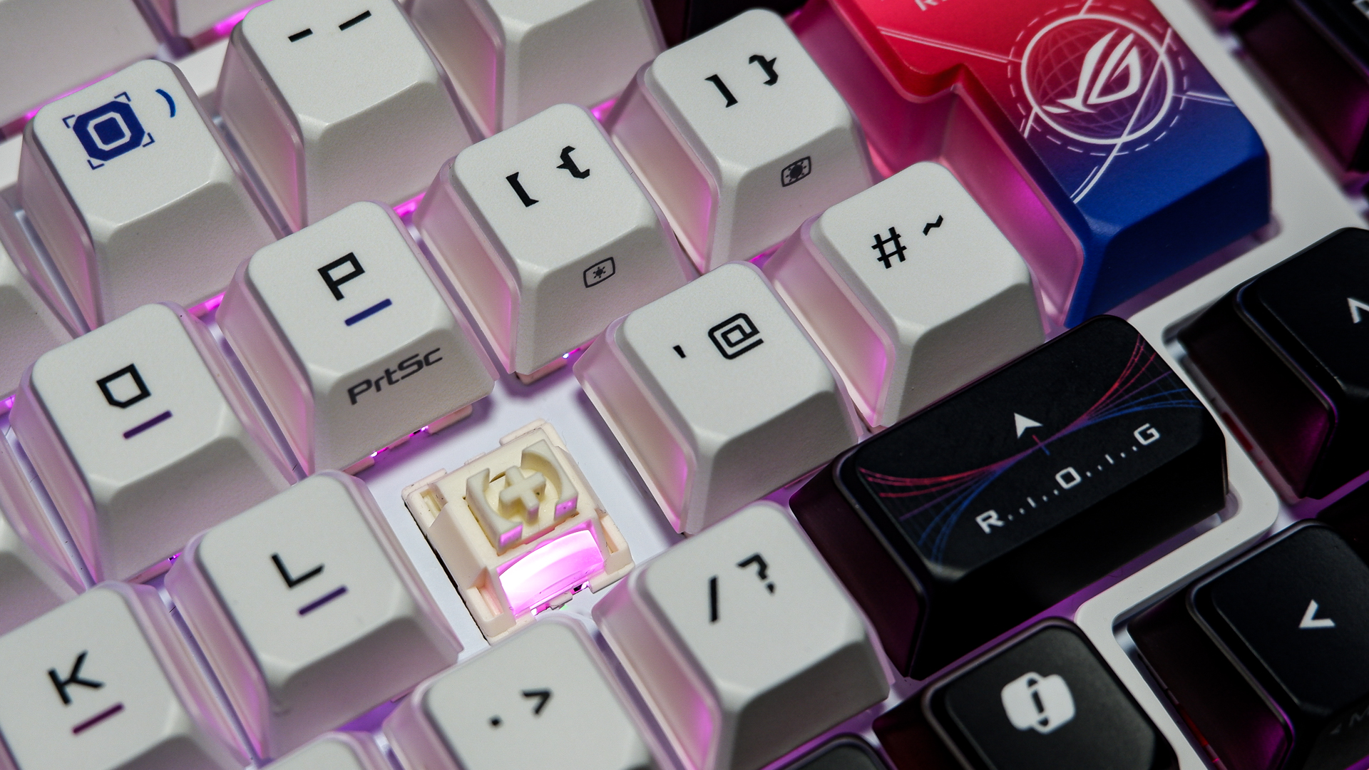 An Asus ROG Azoth X gaming keyboard on a desk with wrist rest and lighting enabled.