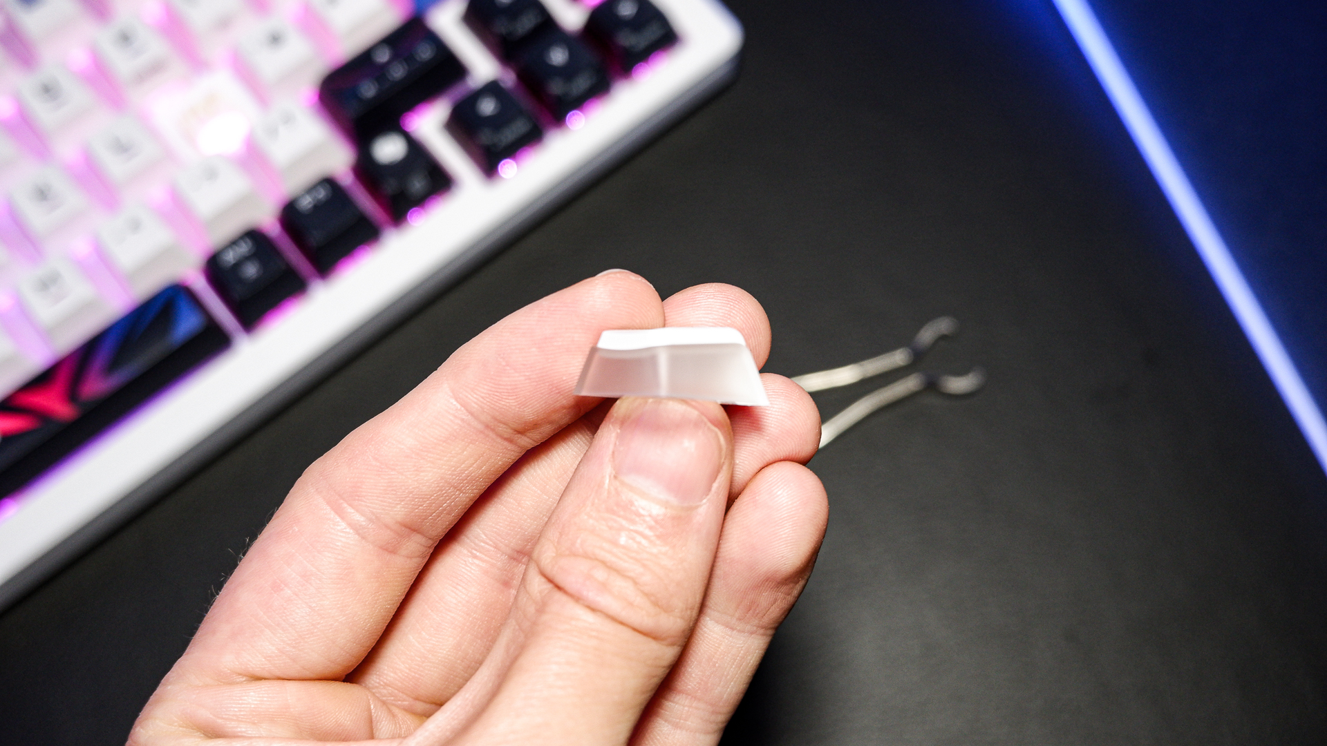 An Asus ROG Azoth X gaming keyboard on a desk with wrist rest and lighting enabled.