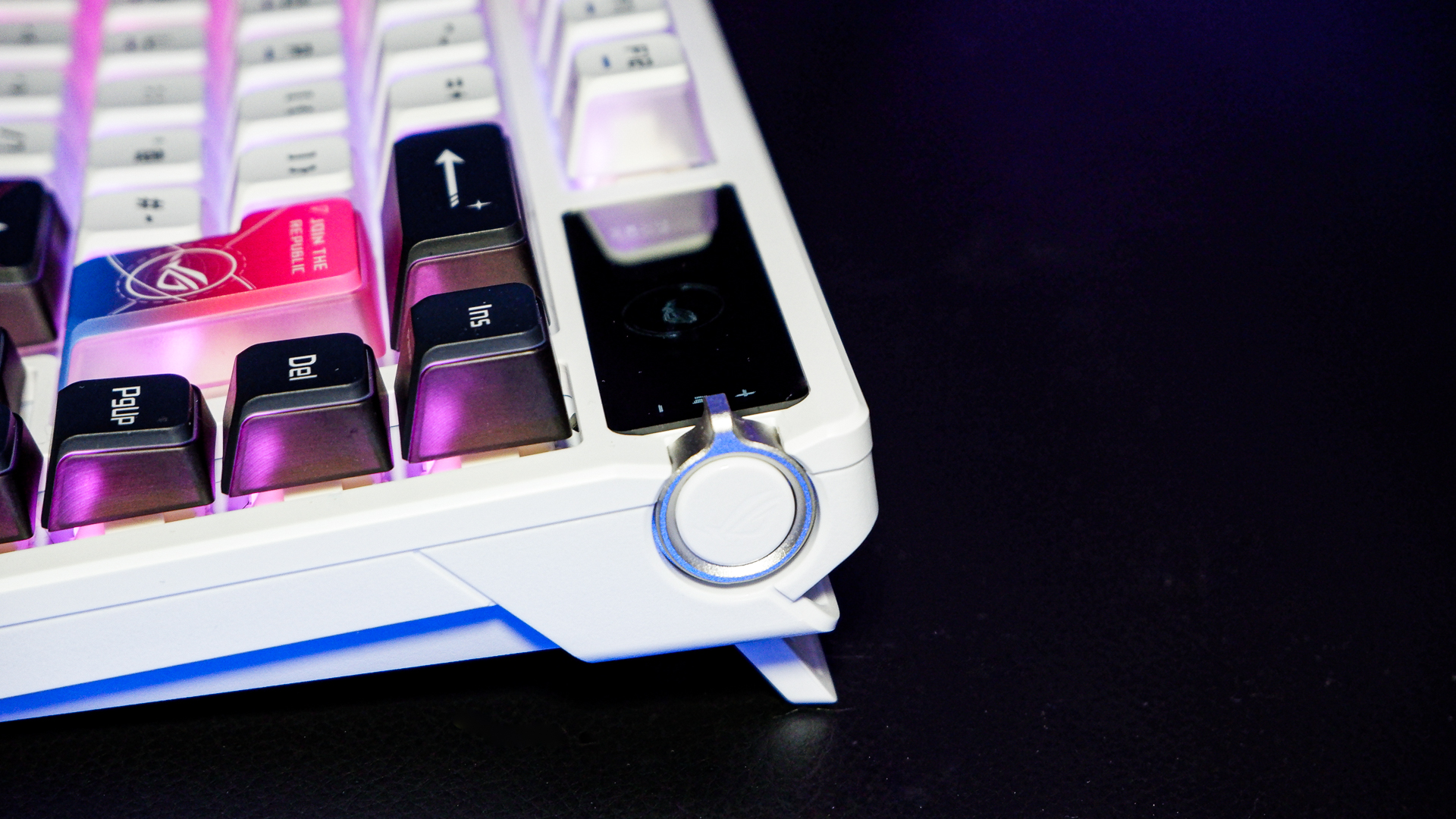 An Asus ROG Azoth X gaming keyboard on a desk with wrist rest and lighting enabled.