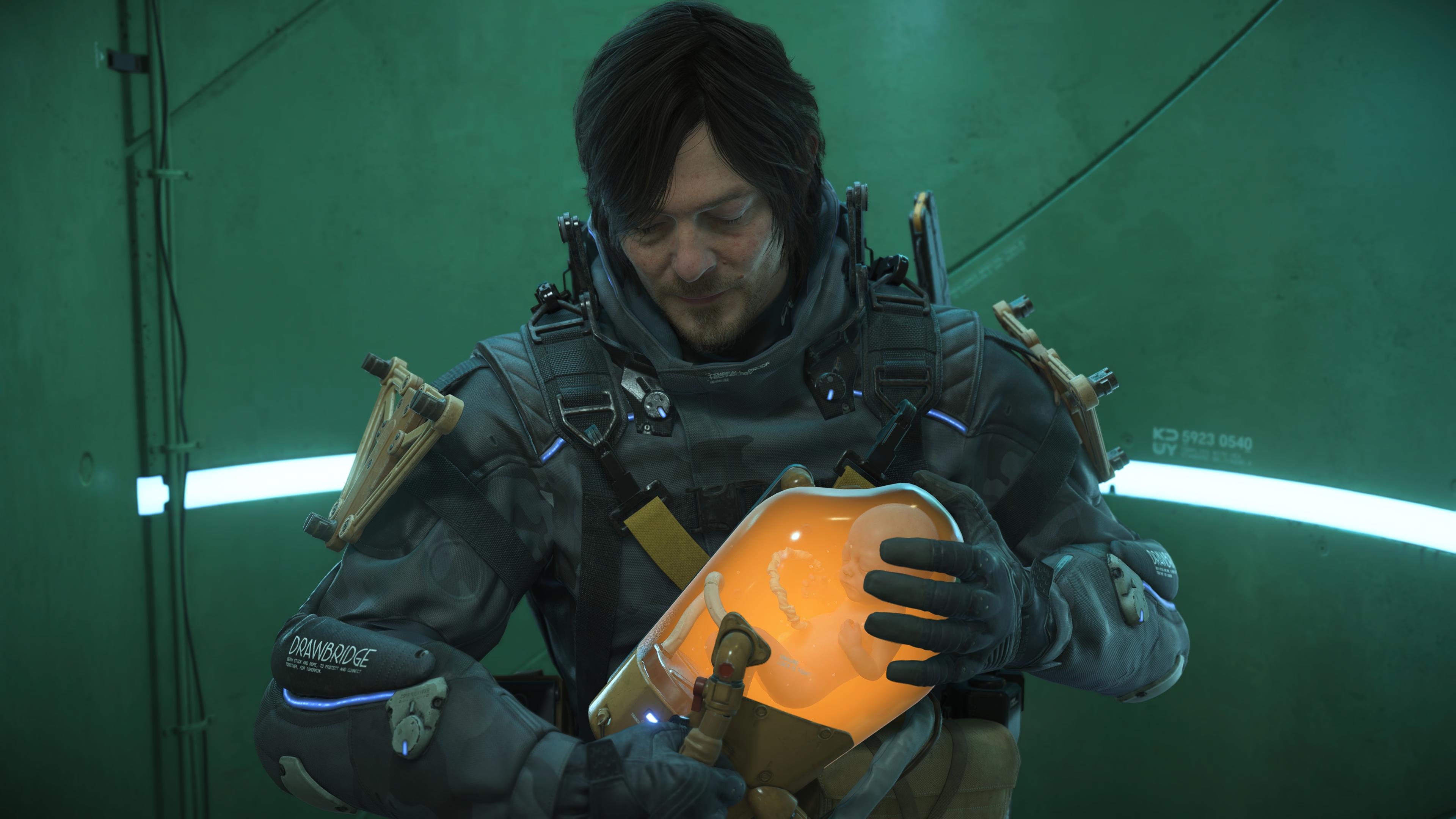 Sam in Death Stranding 2, holding a BB pod with the spirit of Lou inside Sam in Death Stranding 2, holding a BB pod with the spirit of Lou inside