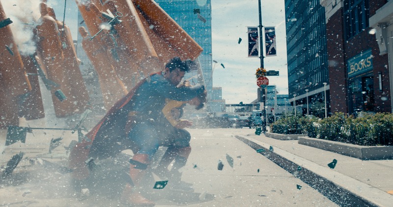 In a still from the 2025 film Superman, Superman saves a small child from death during an explosion on the streets of Metropolis. 