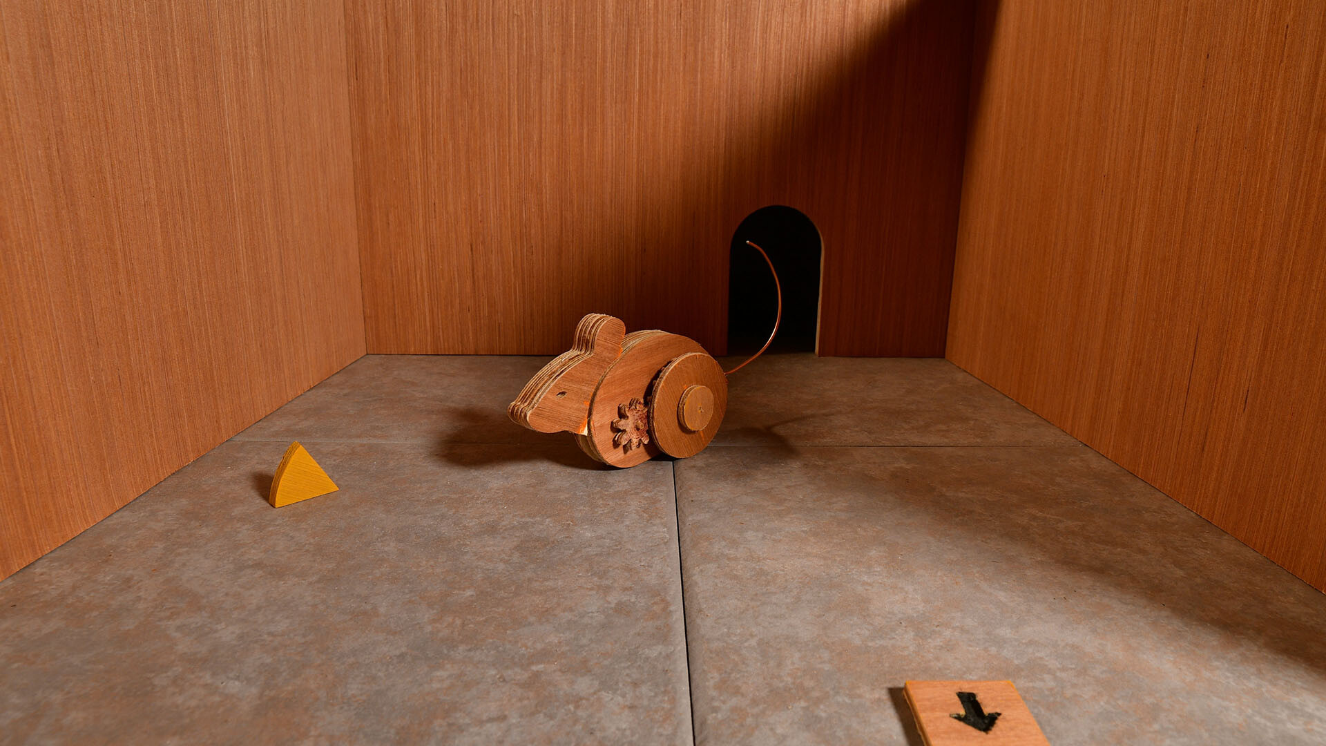 Wooden mouse in empty room with cheese in Ealu