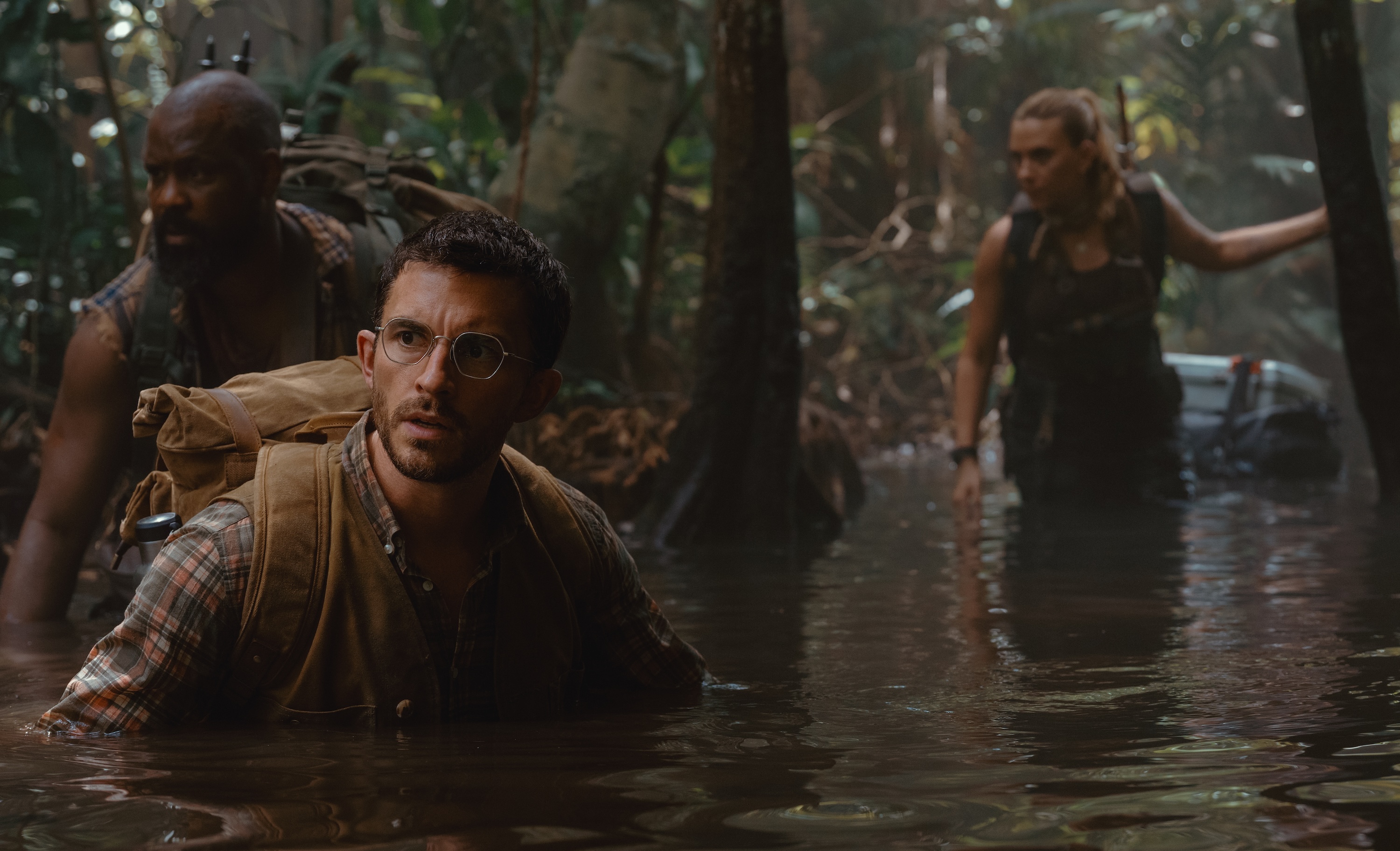 Two men (Bechir Sylvain and Jonathan Bailey) wade chest-deep through a swamp in Jurassic World Rebirth as Scarlett Johansson follows, only thigh deep in the water behind them Two men (Bechir Sylvain and Jonathan Bailey) wade chest-deep through a swamp in Jurassic World Rebirth as Scarlett Johansson follows, only thigh deep in the water behind them