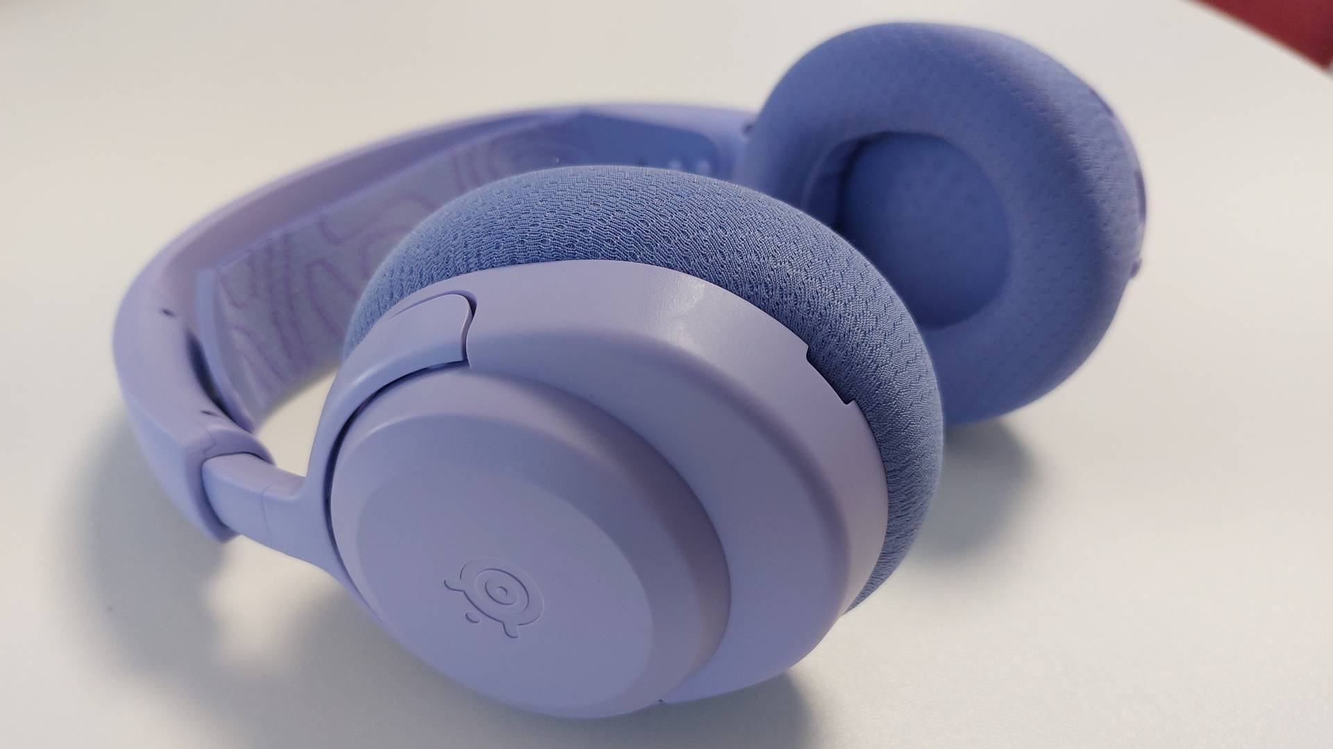 The SteelSeries Arctis Nova 3 X seen on a desk. This is the Lavender colourway.