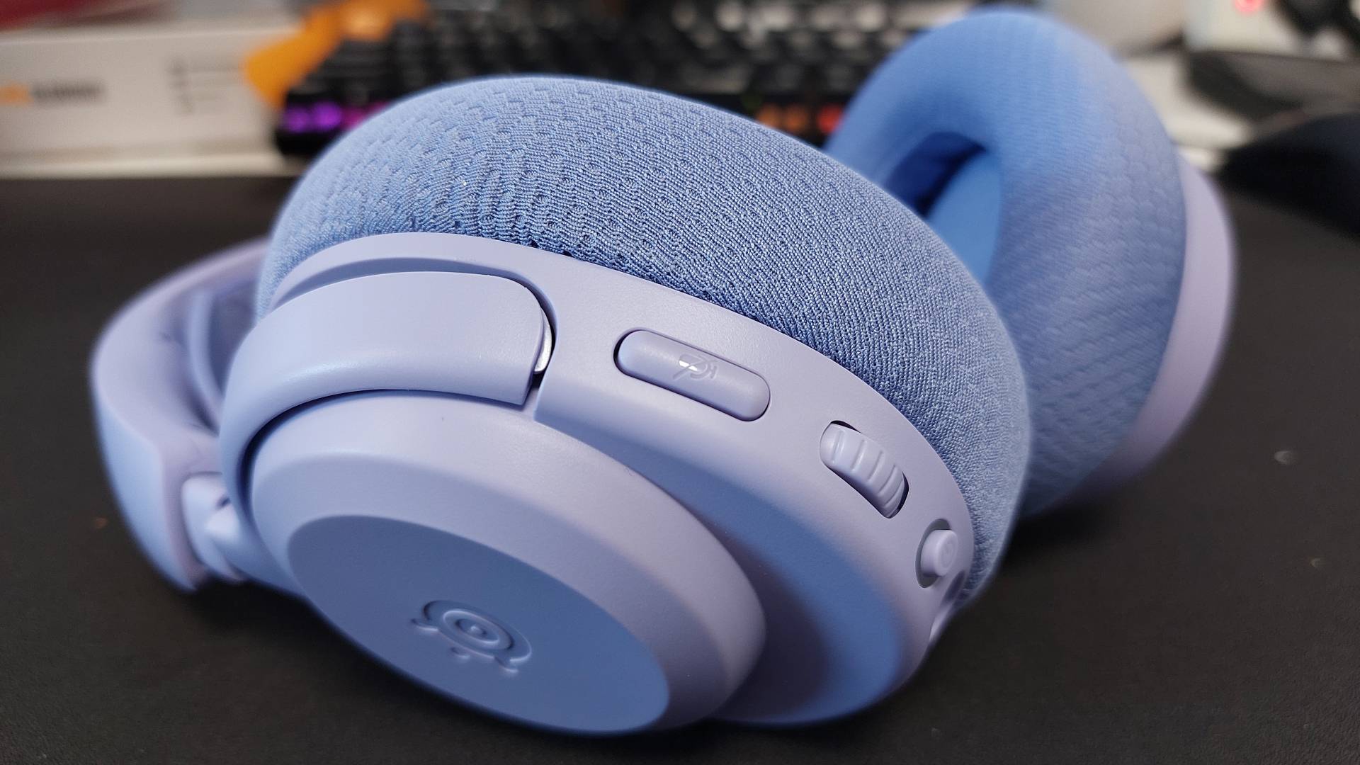 The SteelSeries Arctis Nova 3 X seen on a desk. This is the Lavender colourway.