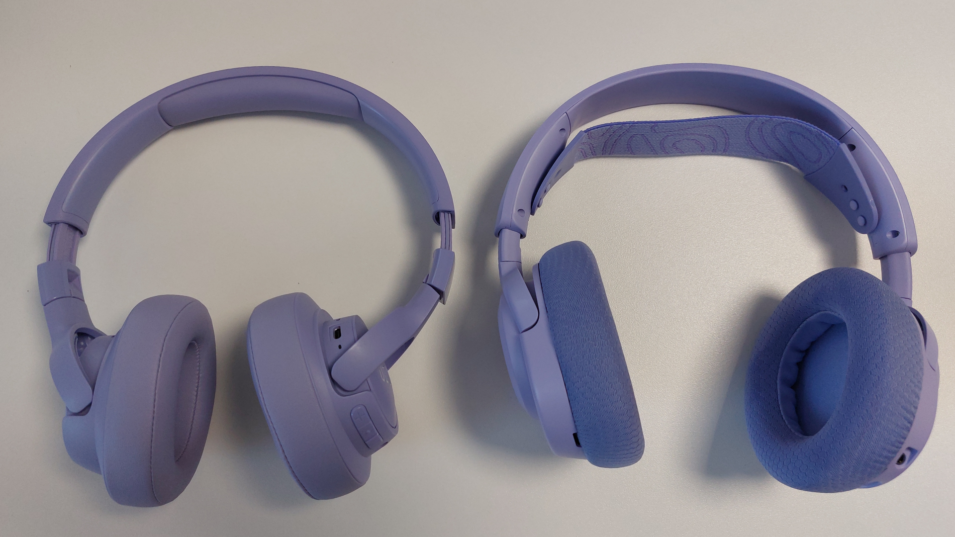 The SteelSeries Arctis Nova 3 X seen on a desk alongside the JBL Tune 720 BT. Both are the Lavender colourway.