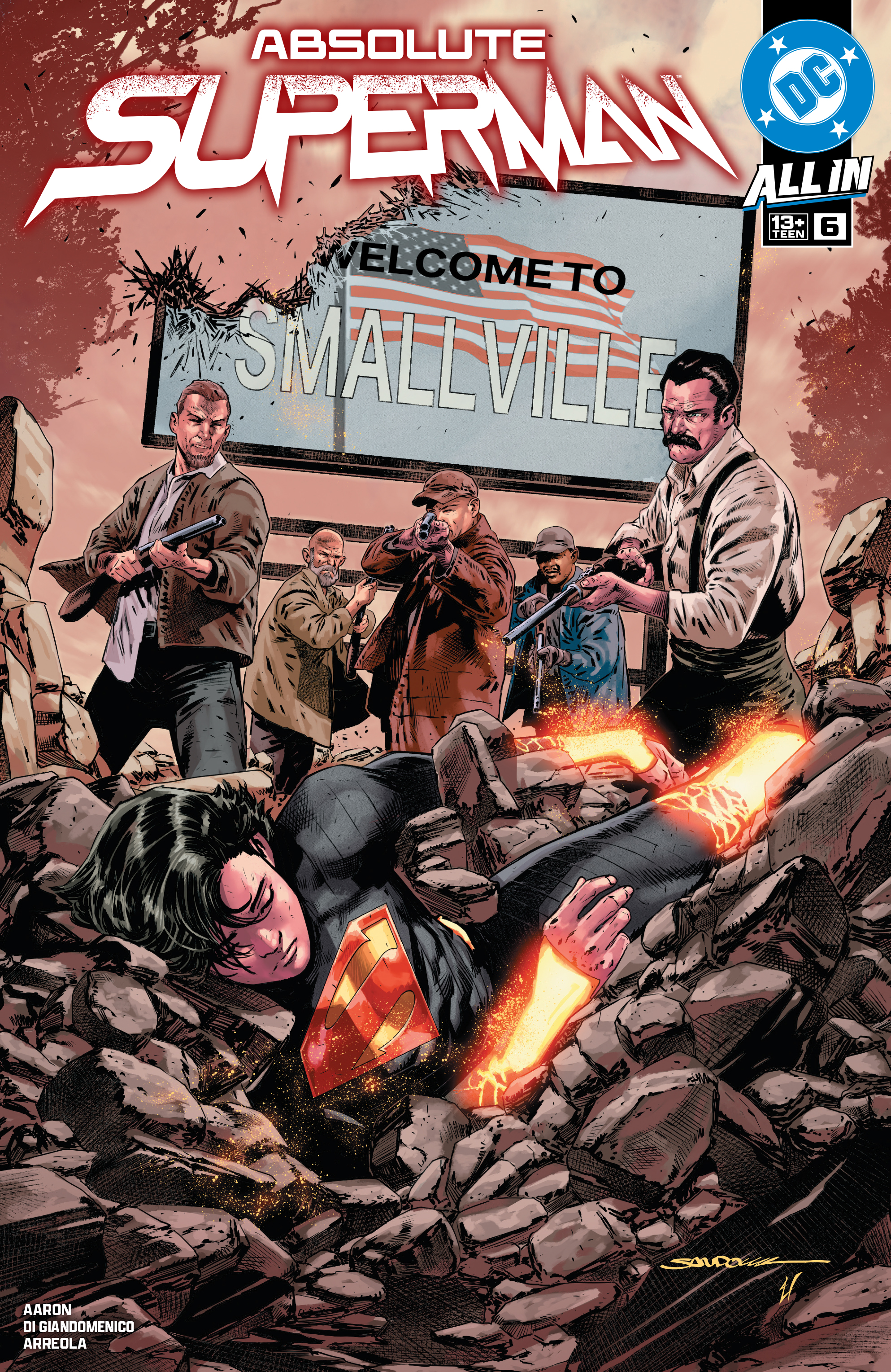 The cover of Absolute Superman #6 shows Kal-El seemingly unconscious and buried in rubble, surrounded by men with guns in front of a “Welcome to Smallville” sign