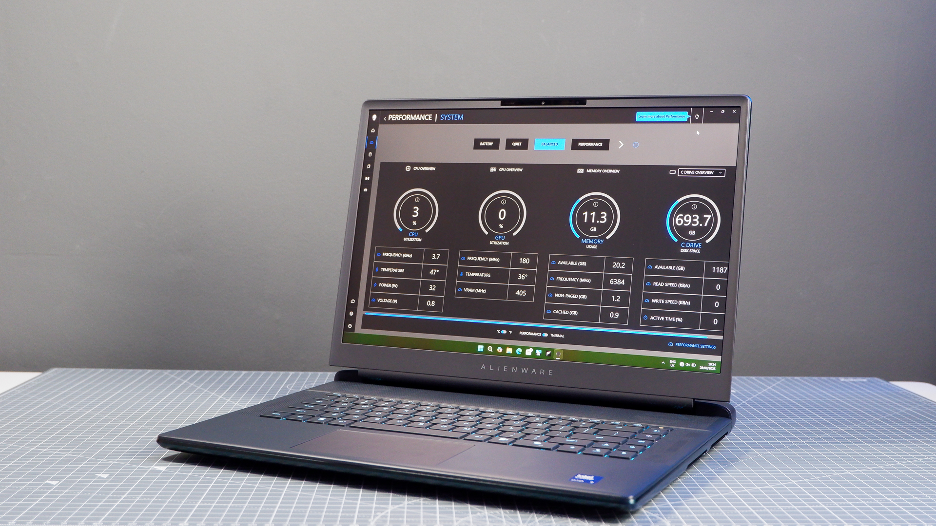 An Alienware 16 Area-51 gaming laptop with RGB lighting in blue on a desk mat.