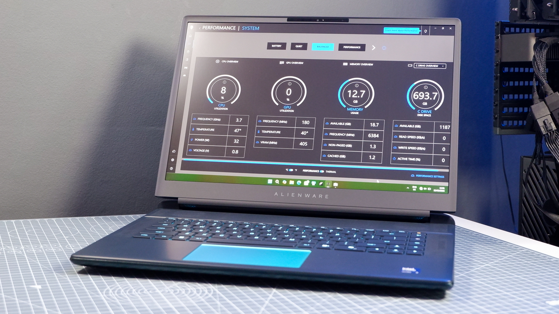 An Alienware 16 Area-51 gaming laptop with RGB lighting in blue on a desk mat.