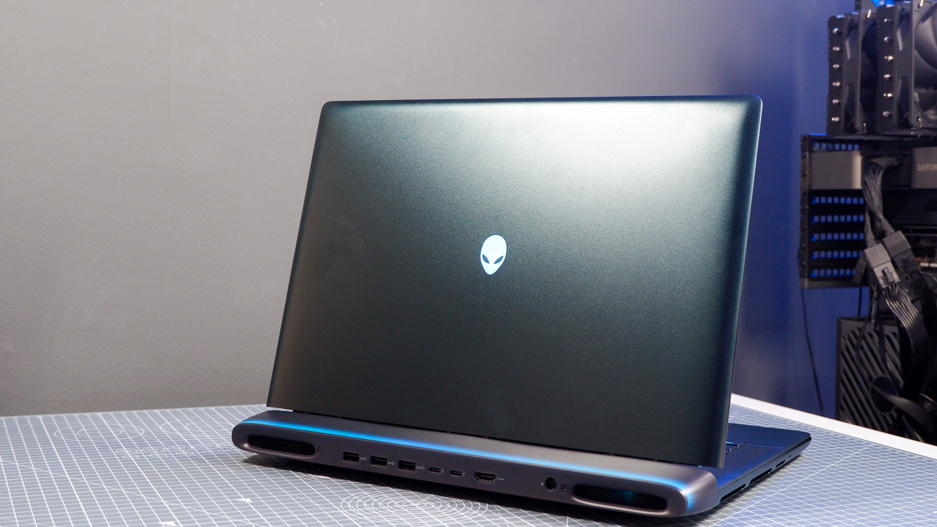 An Alienware 16 Area-51 gaming laptop with RGB lighting in blue on a desk mat.