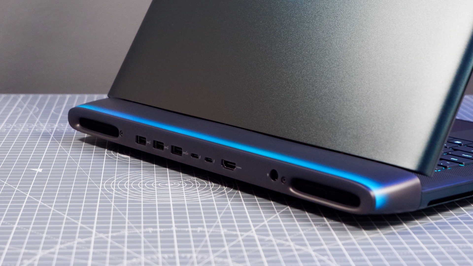 An Alienware 16 Area-51 gaming laptop with RGB lighting in blue on a desk mat.