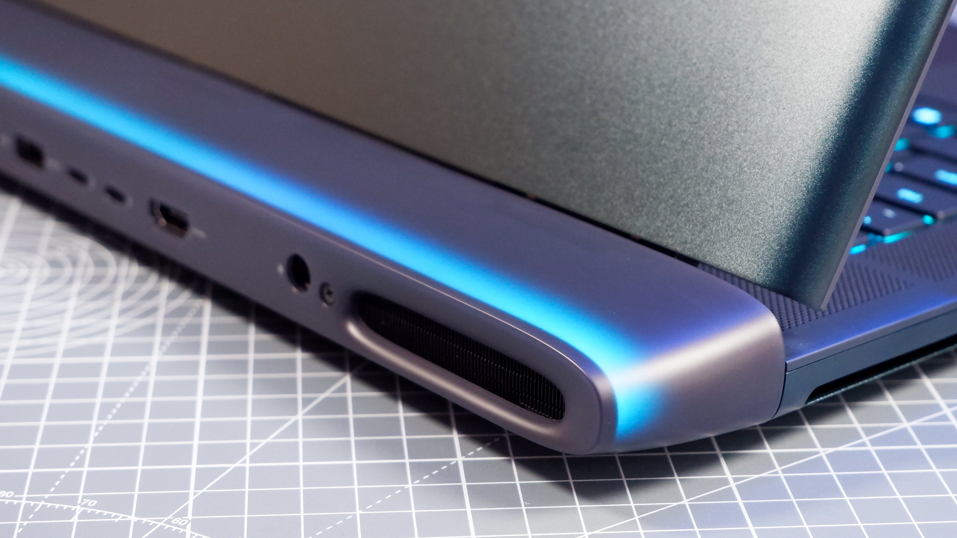 An Alienware 16 Area-51 gaming laptop with RGB lighting in blue on a desk mat.