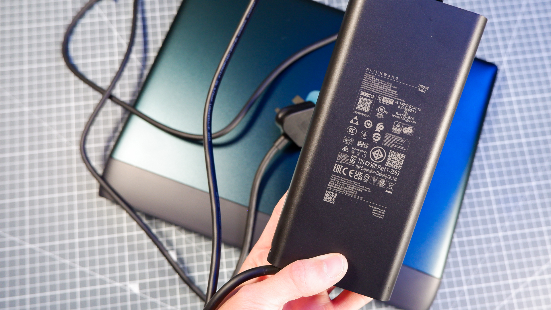 An Alienware 16 Area-51 gaming laptop with RGB lighting in blue on a desk mat.