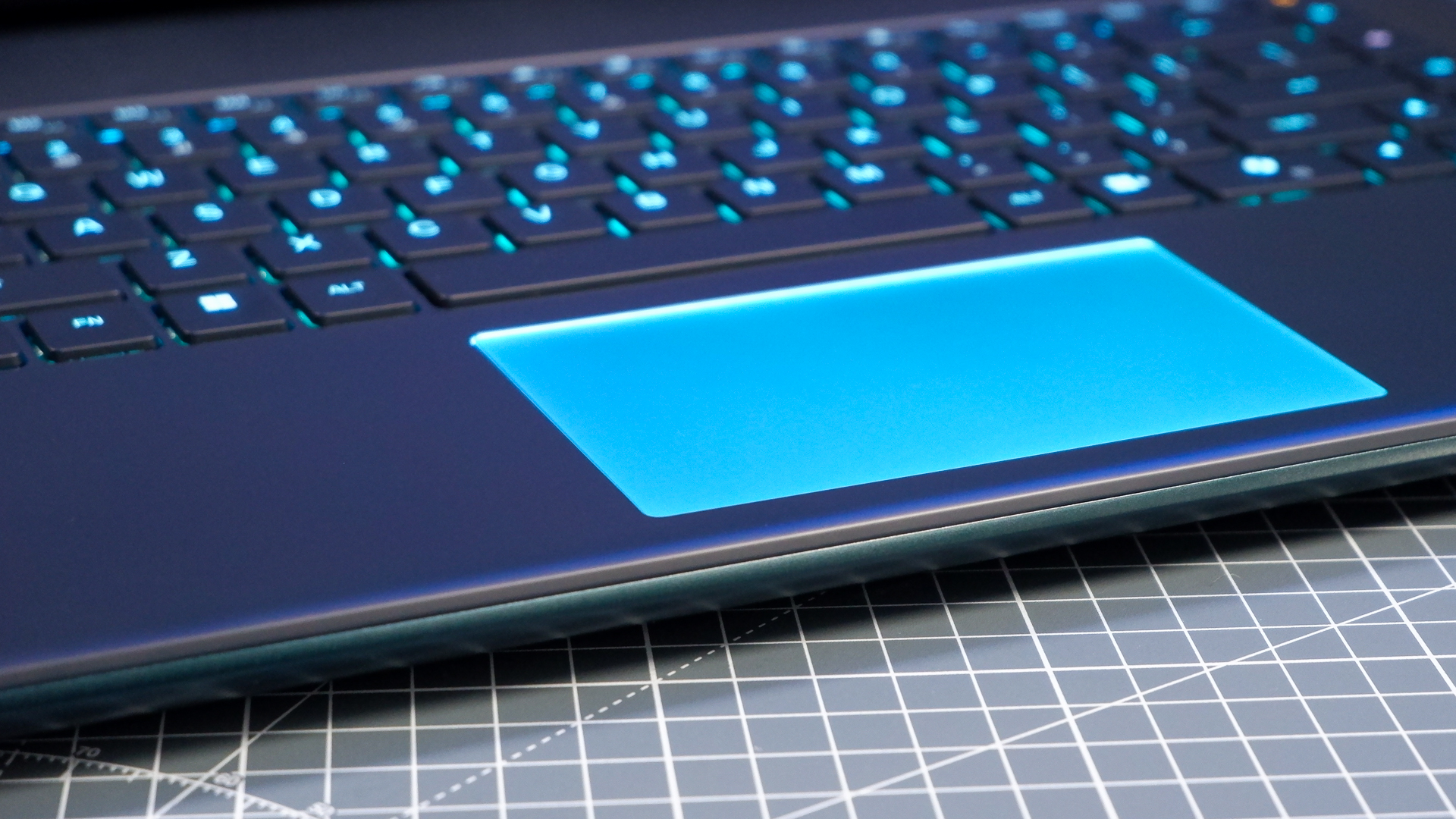 An Alienware 16 Area-51 gaming laptop with RGB lighting in blue on a desk mat.