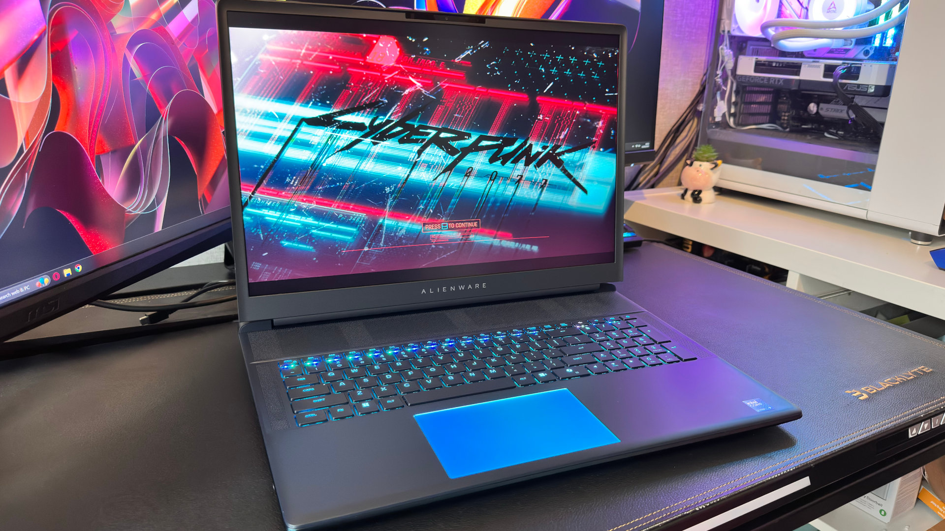 A photo of the Alienware 18 Area-51 gaming laptop, with its display showing the load screen of Cyberpunk 2077