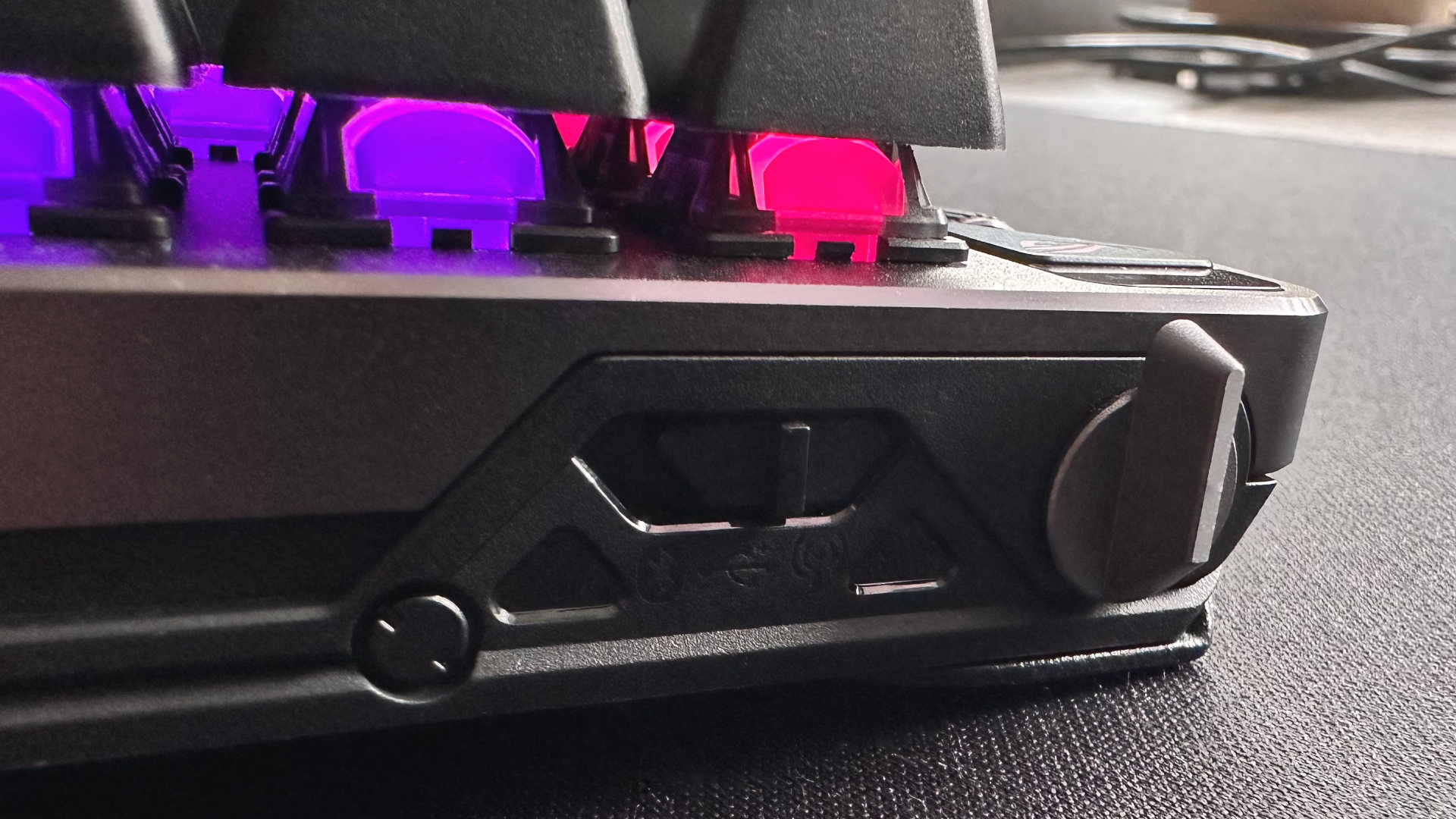 A close-up photo of the Asus ROG Falcata gaming keyboard, showing the toggle switches for connectivity and rapid trigger
