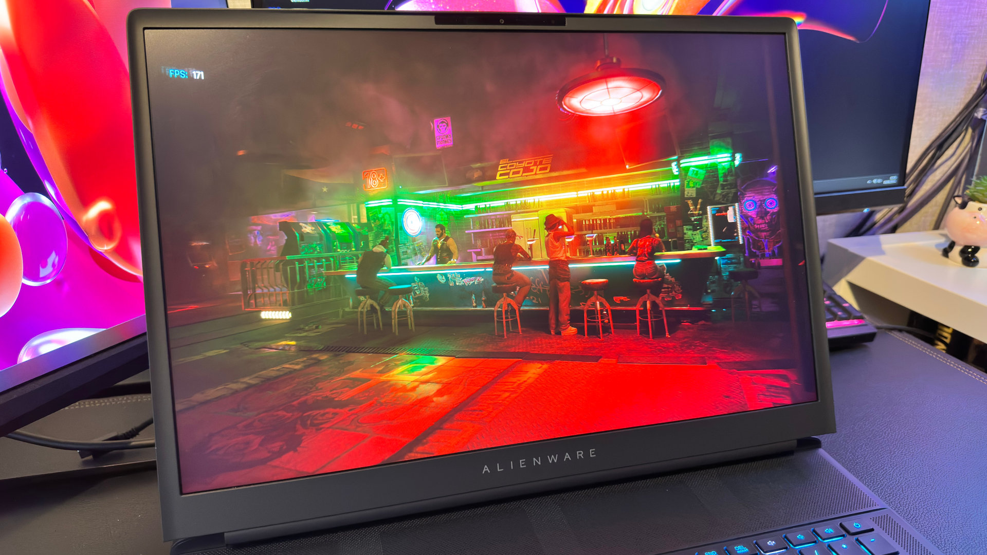 A photo of the Alienware 18 Area-51 gaming laptop, with its display showing Cyberpunk 2077's benchmark mode