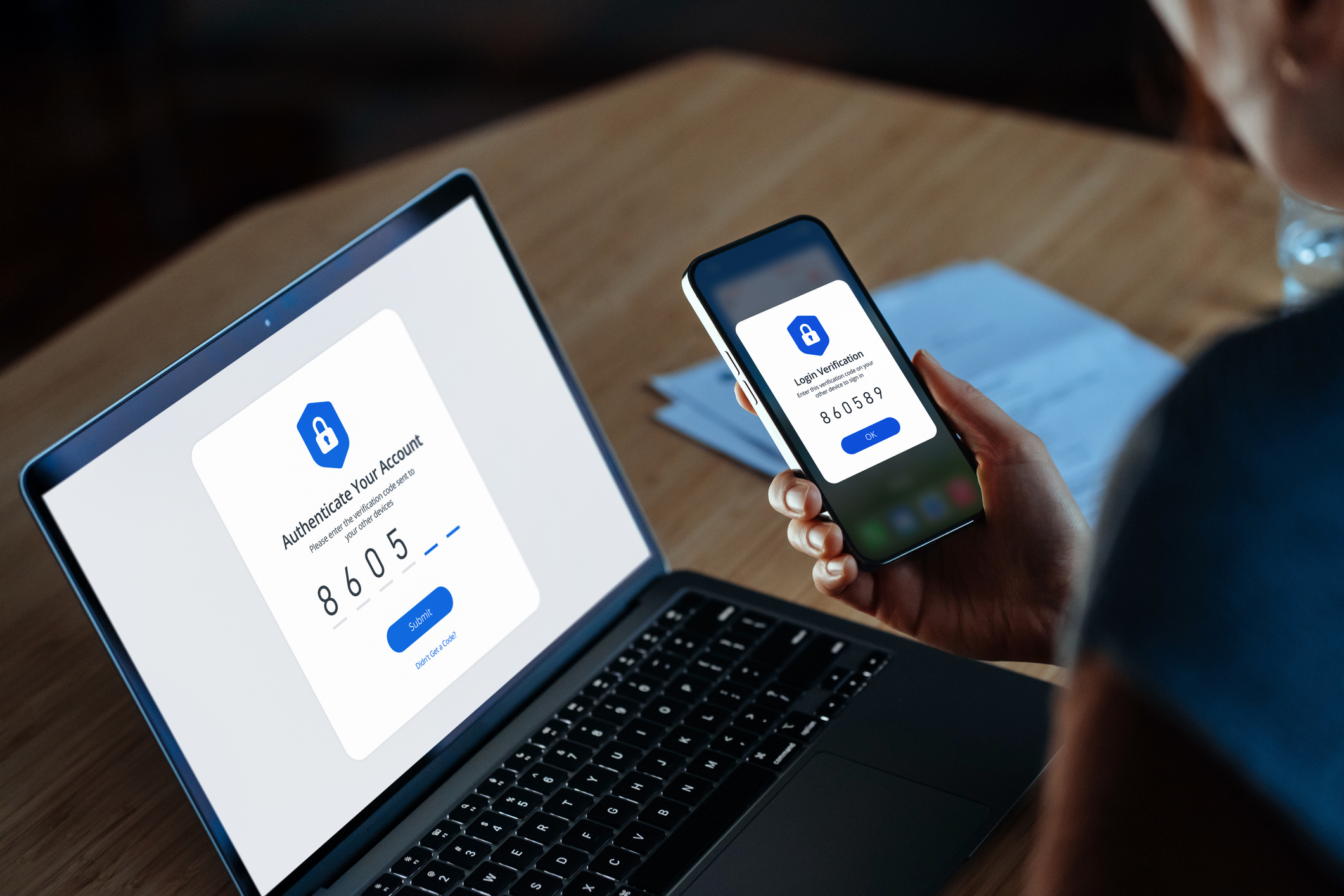 Over the shoulder view of young woman using mobile device with Two-Factor Authentication (2FA) security while logging in securely to her laptop. Privacy protection, internet and mobile security - stock photo