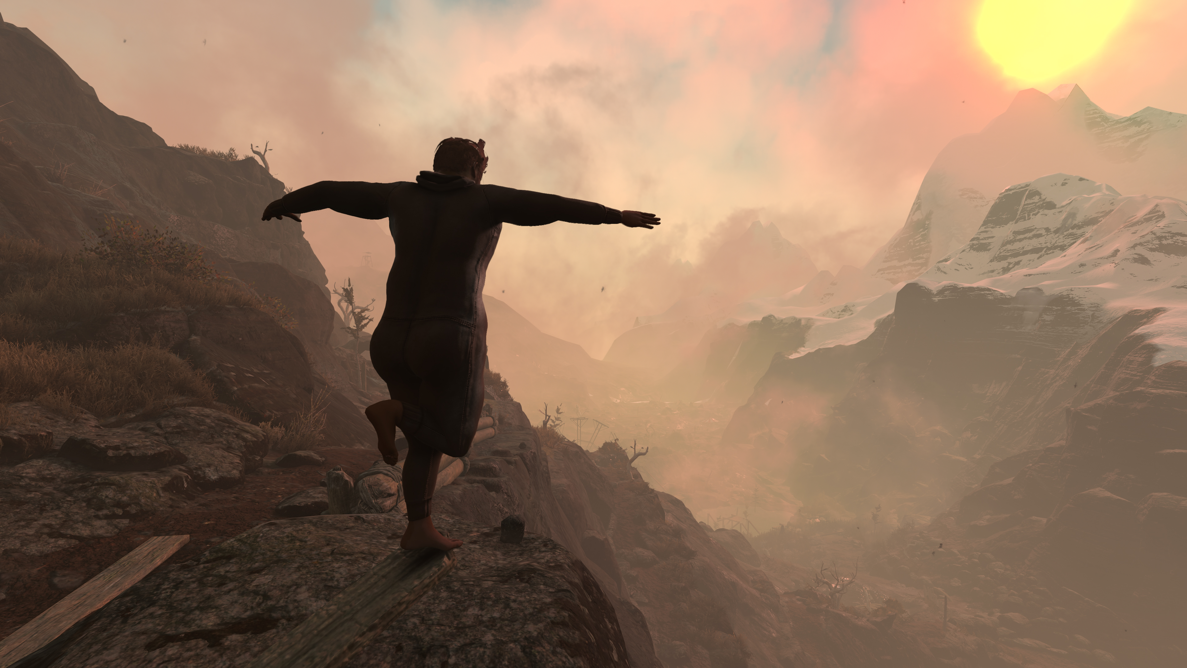 A man walking near the edge of a cliff with a mountain in the distance