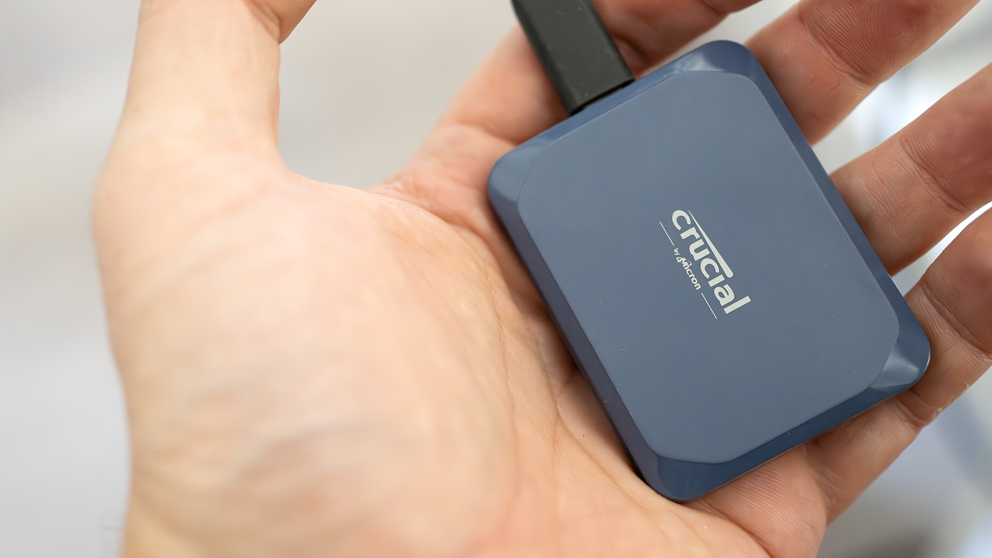 A Crucial X10 external SSD in blue with USB Type-C connector cable.