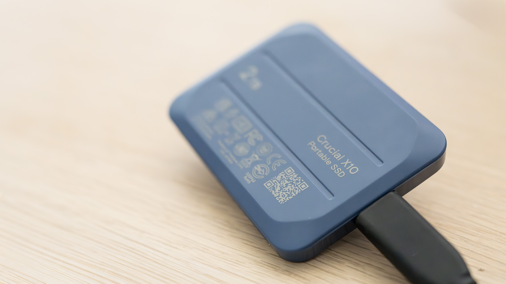 A Crucial X10 external SSD in blue with USB Type-C connector cable.