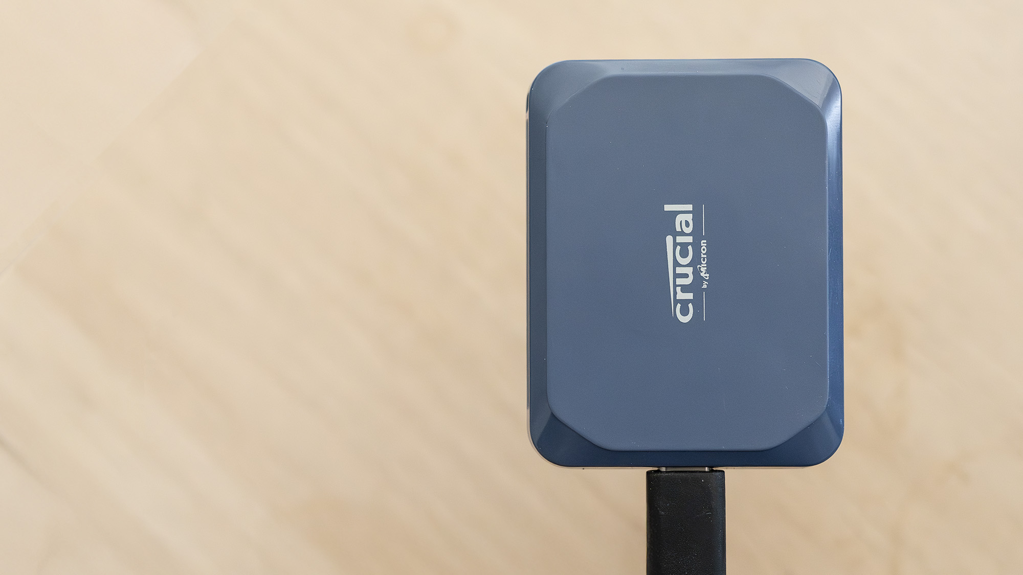 A Crucial X10 external SSD in blue with USB Type-C connector cable.