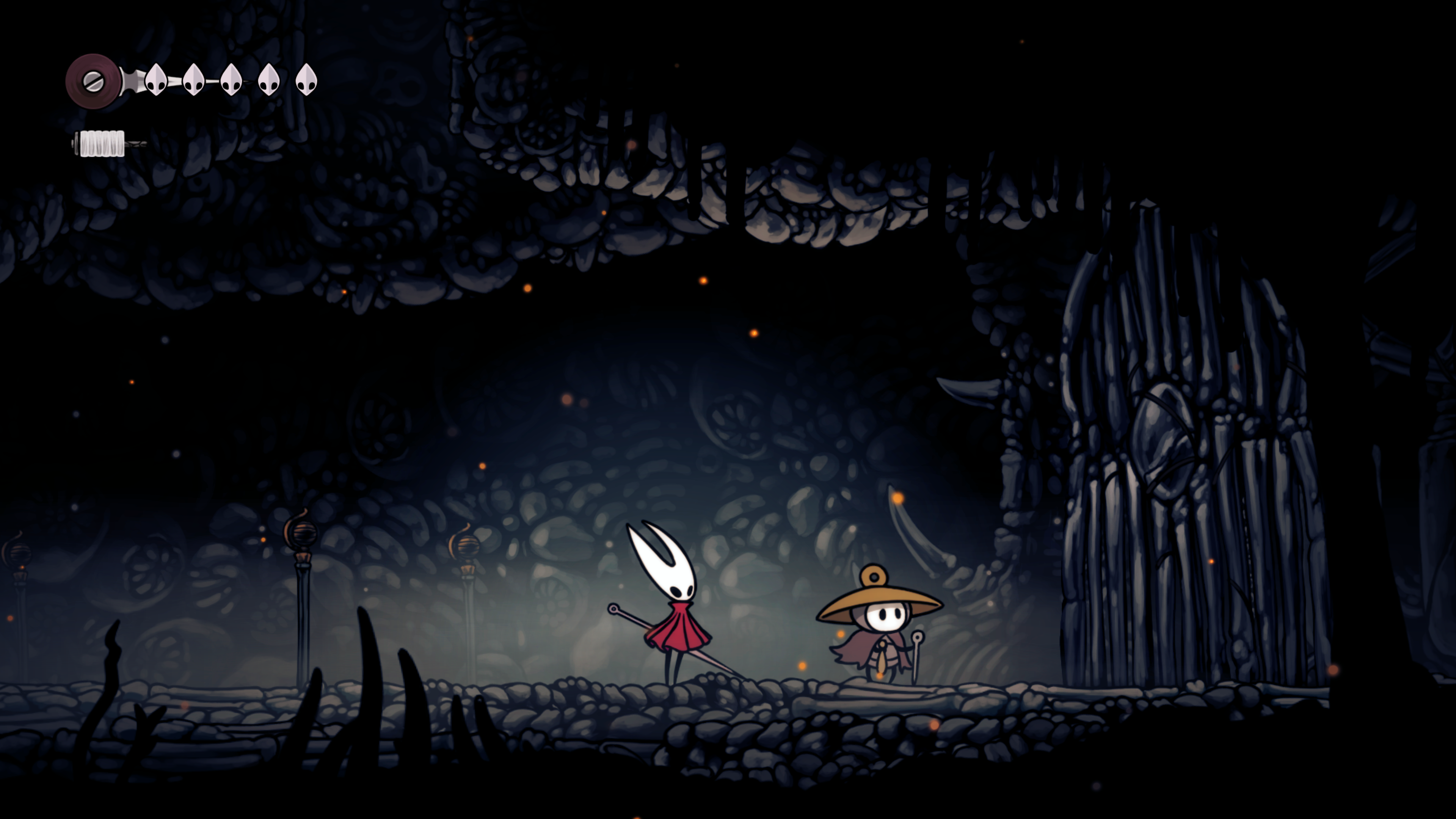A screenshot of Hollow Knight: Silksong. Main character Hornet with her white mask and red cape, stands next to a shorter character with a white mask and a hat in front of a large gate.