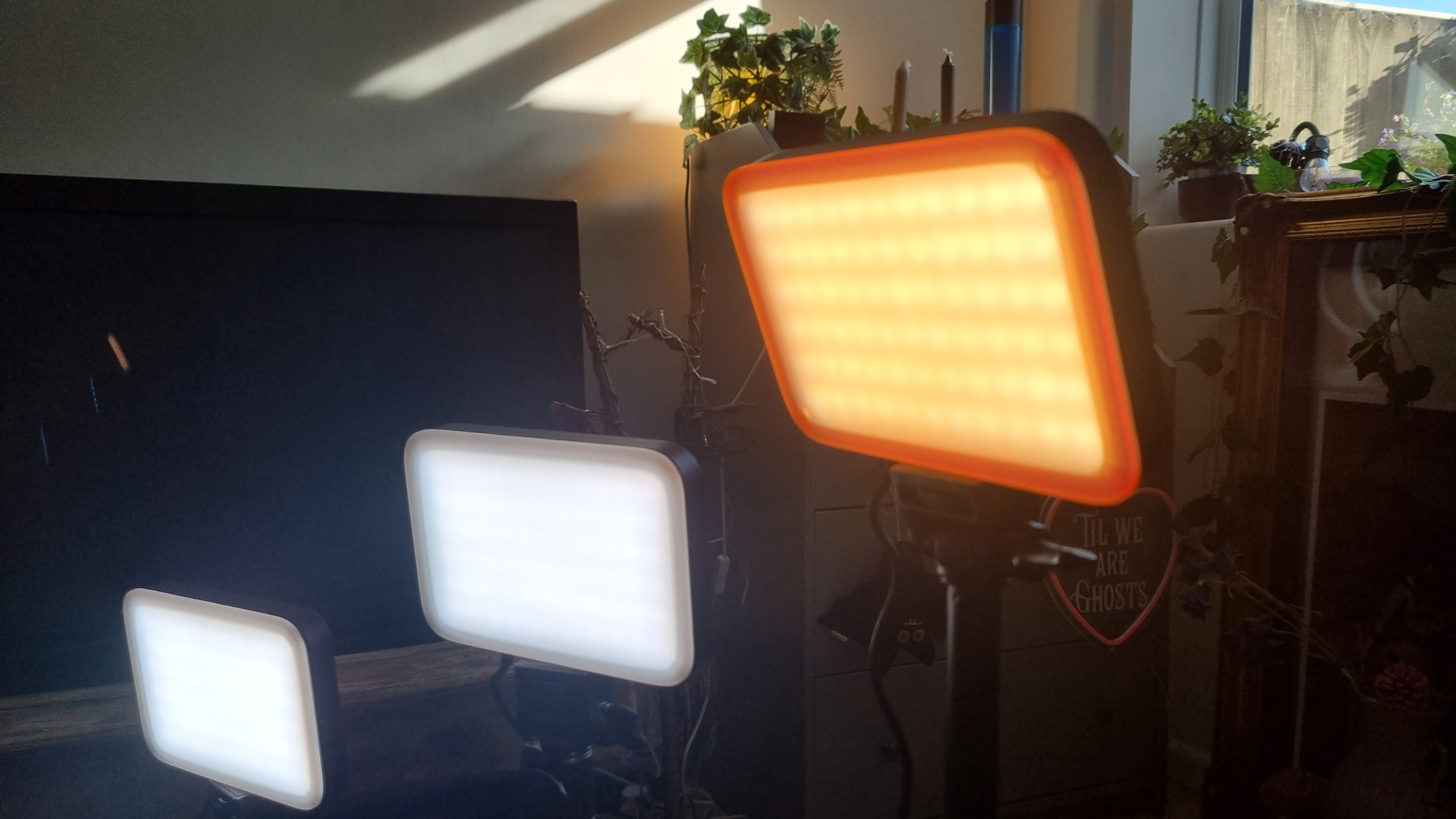 Three panels of the Neewer Basics LED Panel Video Lighting kit, one with an orange diffuser over the LEDS