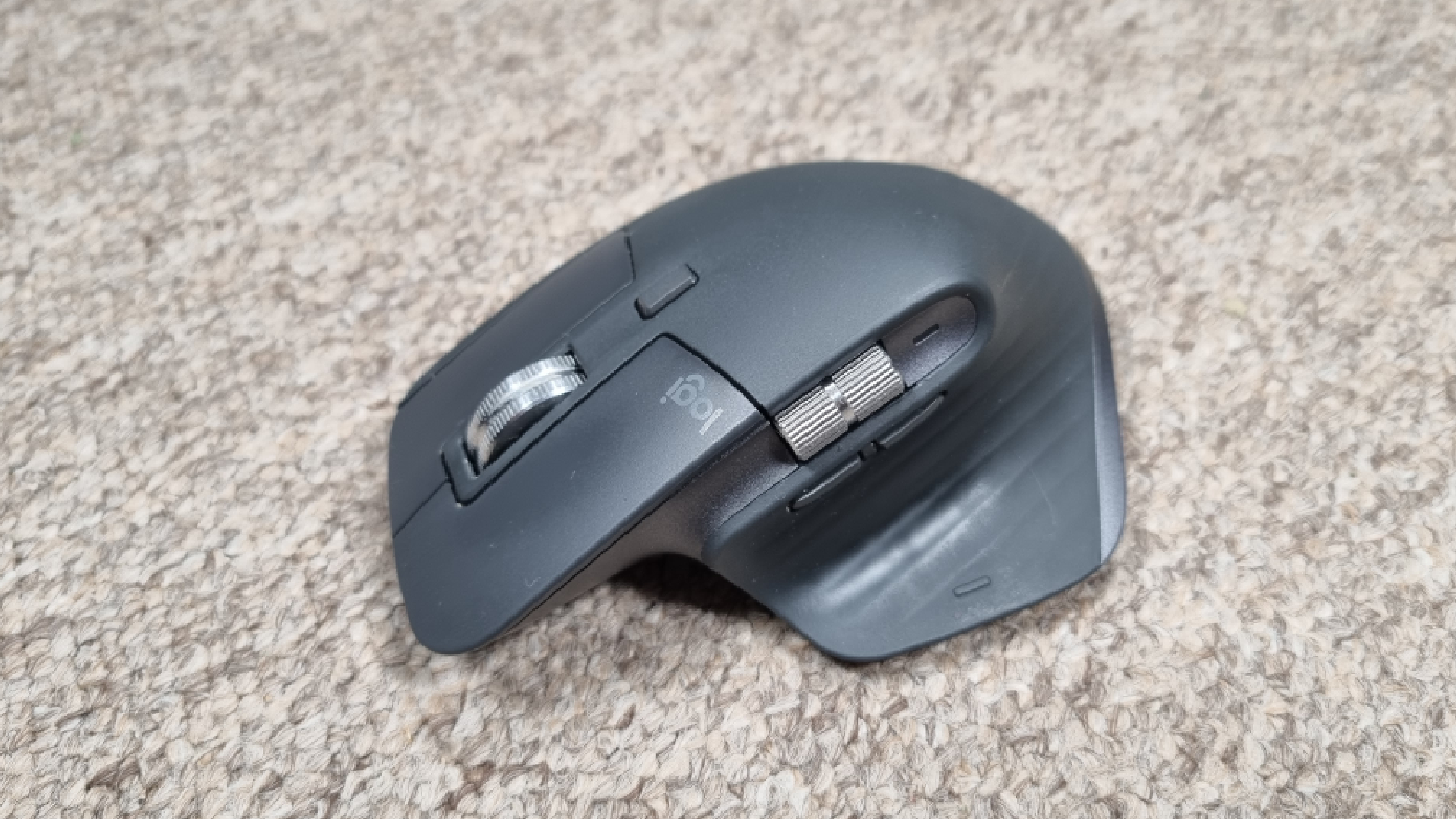 A Logitech MX Master 3S mouse on carpet, with a bright white light above it