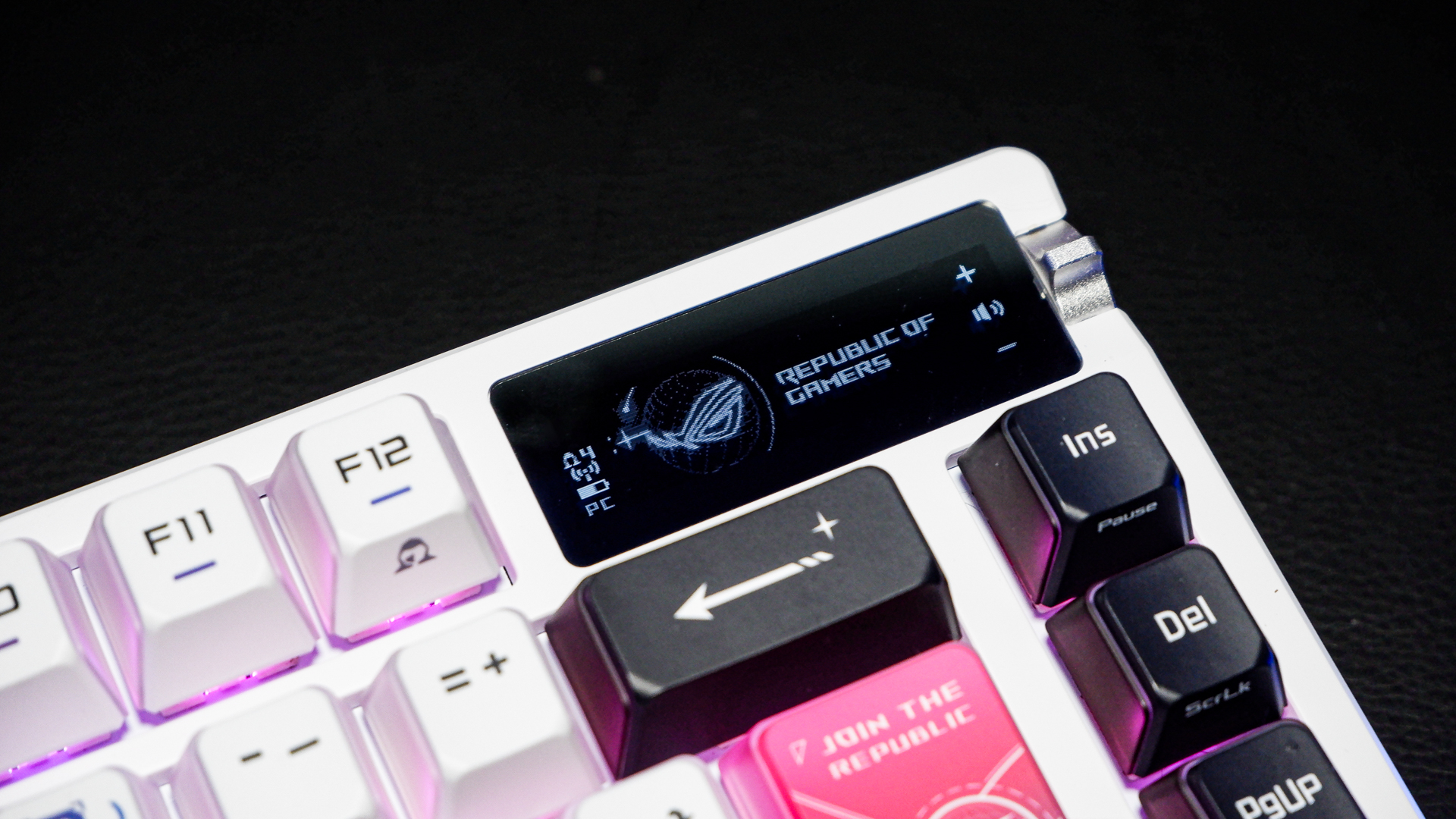 An Asus ROG Azoth X gaming keyboard on a desk with wrist rest and lighting enabled.