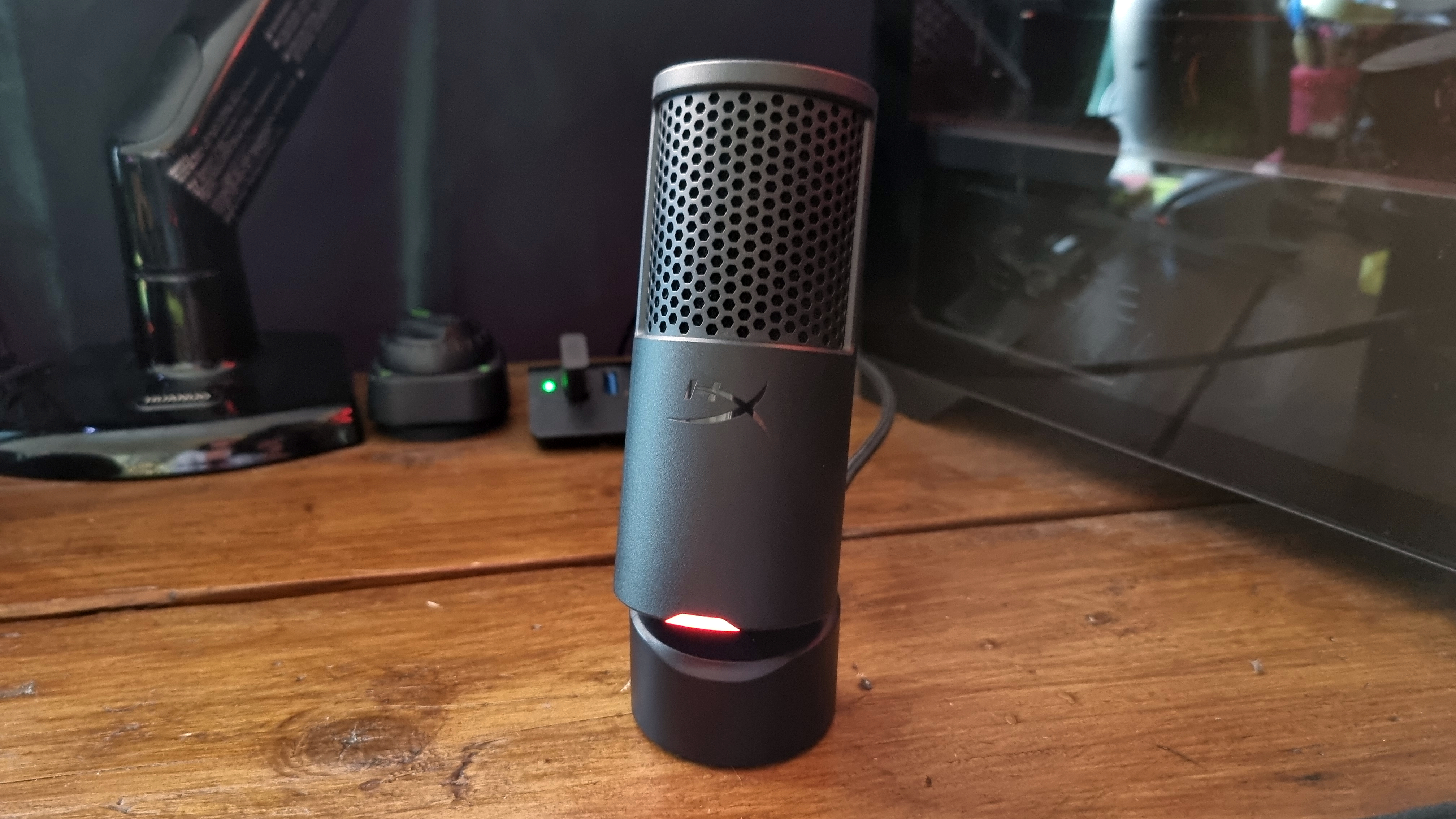 The HyperX SoloCast 2 on a desk, with the red light on
