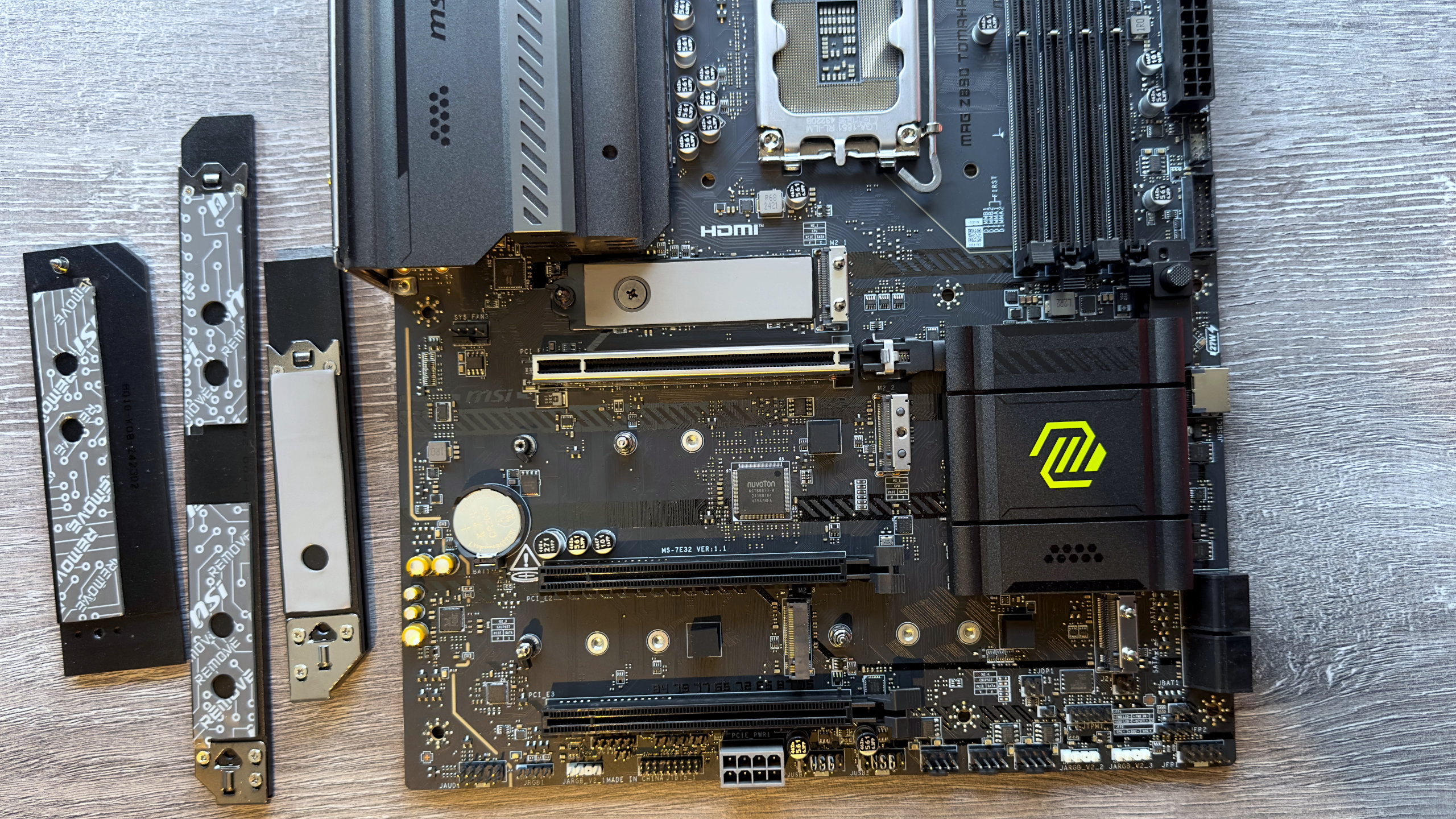 A photo of the MSI MAG Z890 Tomahawk WiFi motherboard, showing the M.2 heatsinks removed and next to the board.