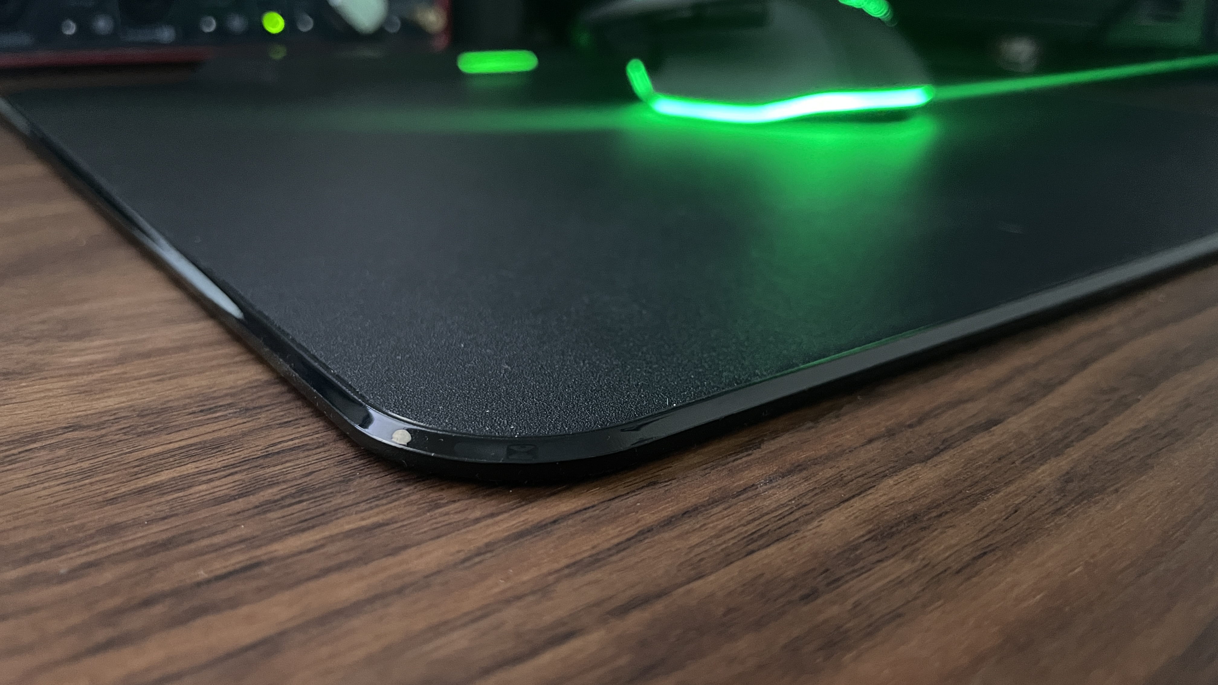 A close-up of the glossy edge of the Razer HyperFlux V2 charging mouse pad.