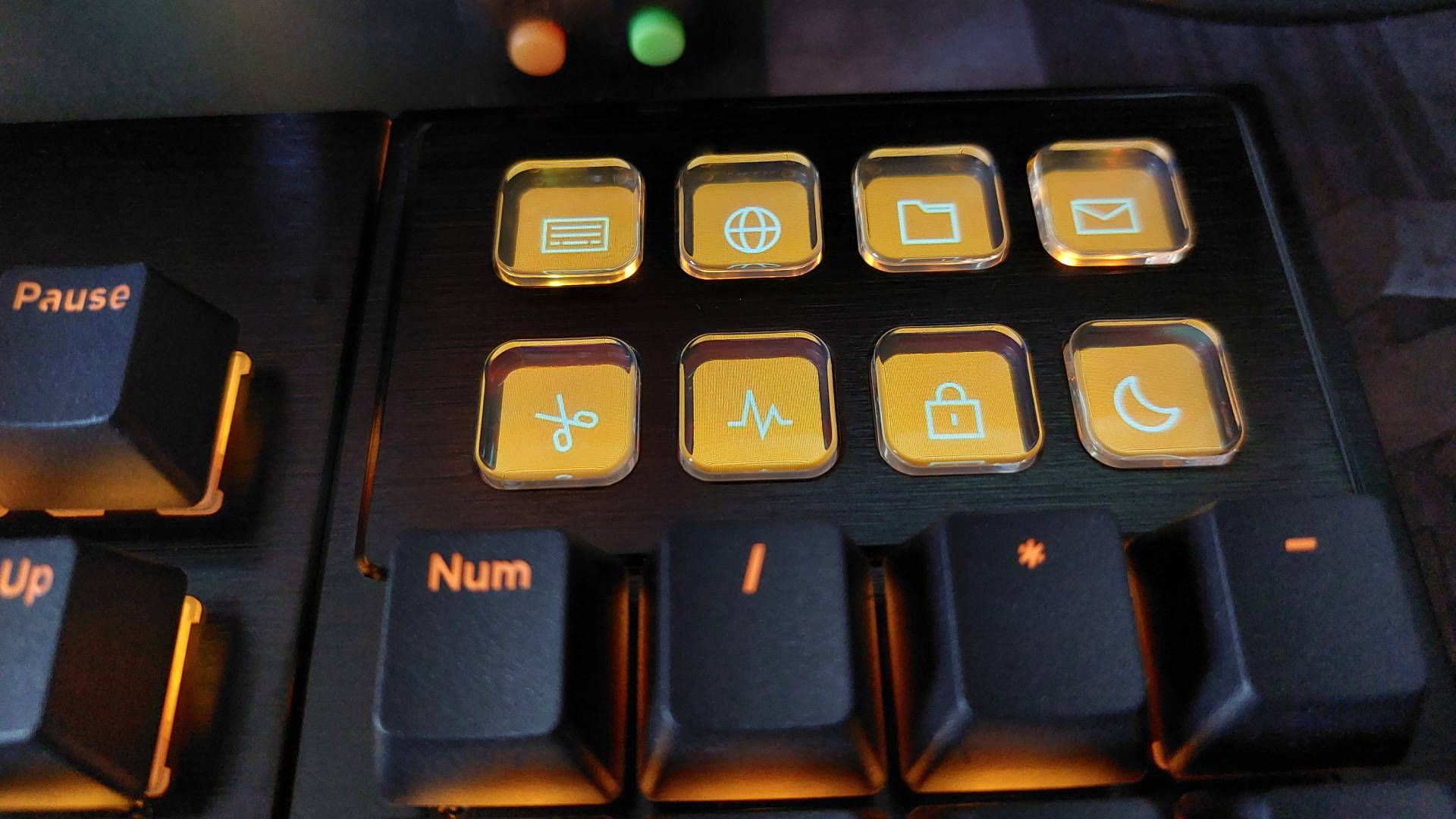 A close up of the Dark Mount mechanical keyboard from be quiet! Here, we see the top row of buttons on the modular numberpad attachment. Rather than the typical PBT keys on the rest of the board, these eight buttons are low profile and plastic, intended to be remapped by the user. The RGB lights are on, bathing everything in an orange glow.