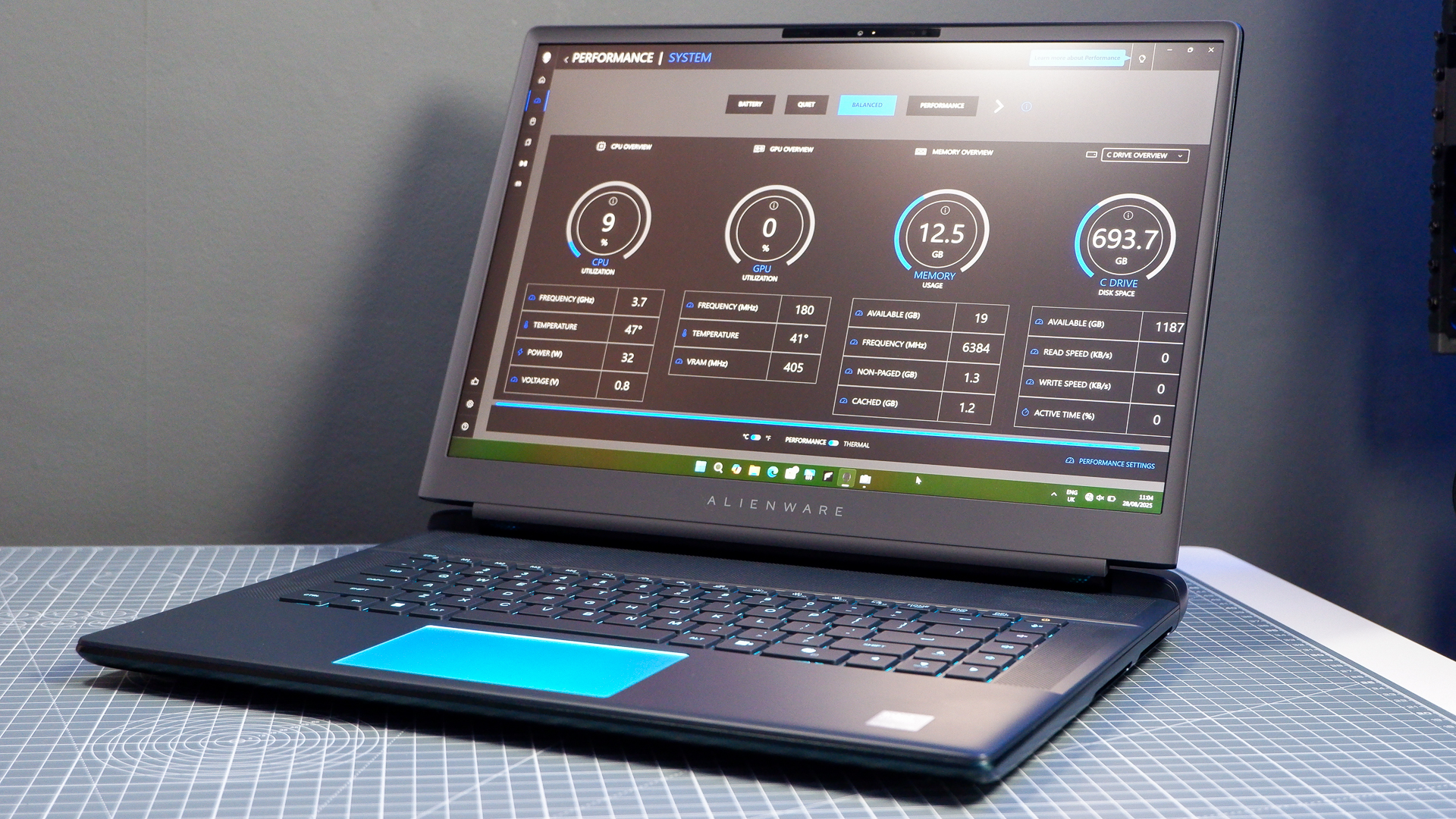 An Alienware 16 Area-51 gaming laptop with RGB lighting in blue on a desk mat.