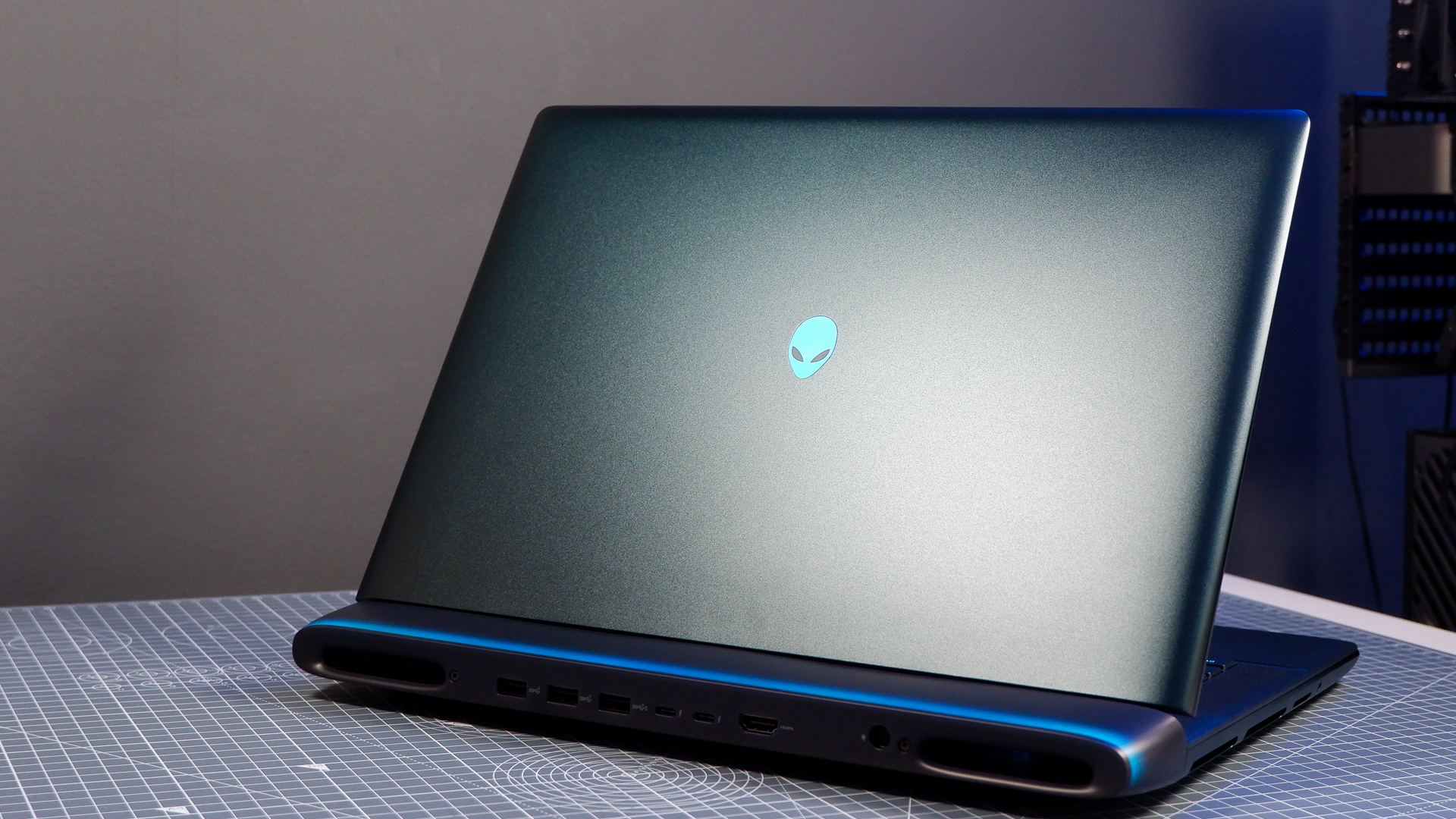 An Alienware 16 Area-51 gaming laptop with RGB lighting in blue on a desk mat.
