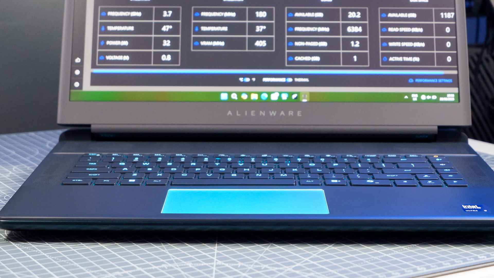 An Alienware 16 Area-51 gaming laptop with RGB lighting in blue on a desk mat.