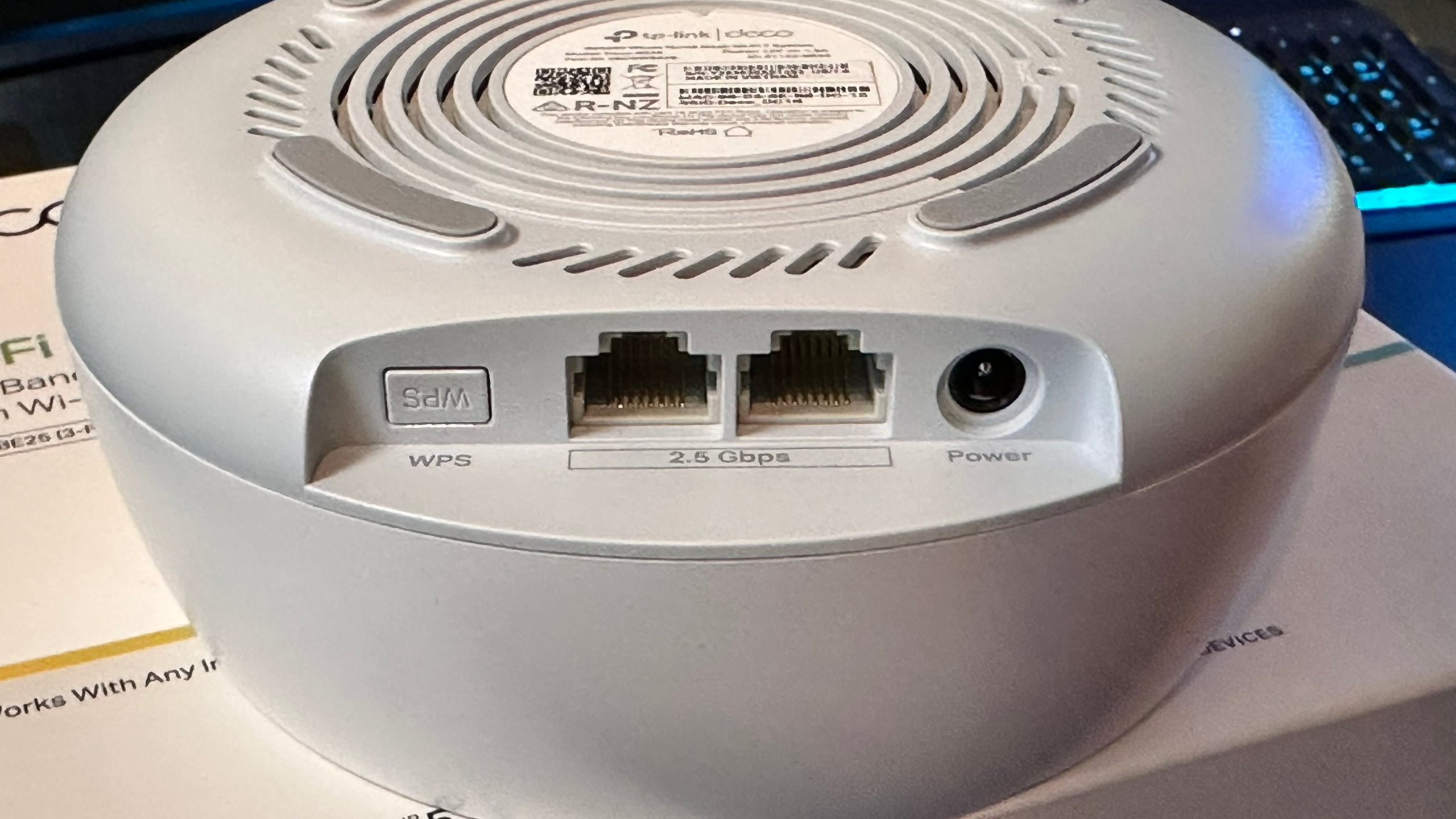 A photo of the underside of a TP-Link Deco BE25 mesh router showing its WAN/LAN ports.
