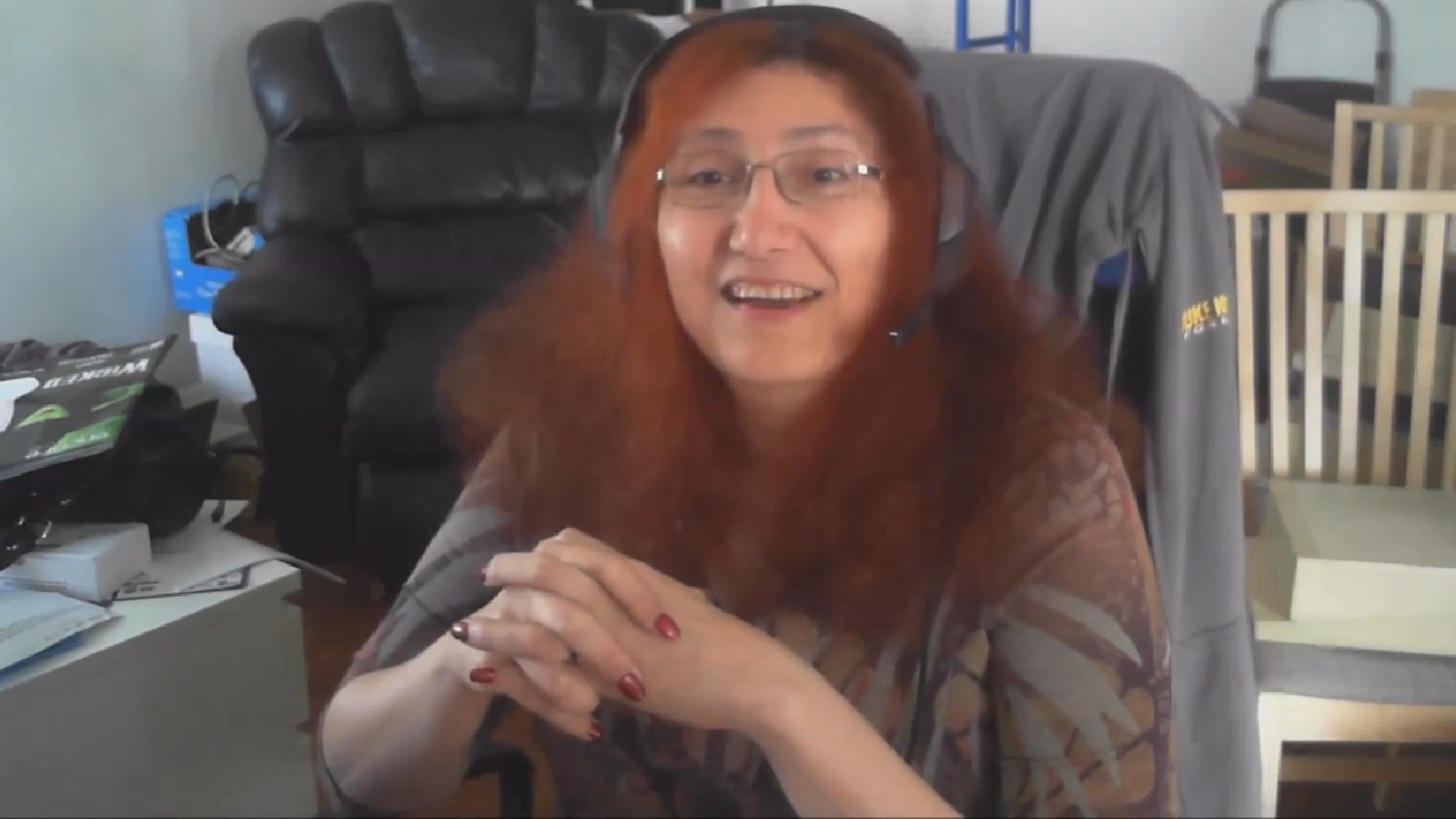 Videogame programmer Rebecca Heineman sitting in home office with clasped hands addressing camera.